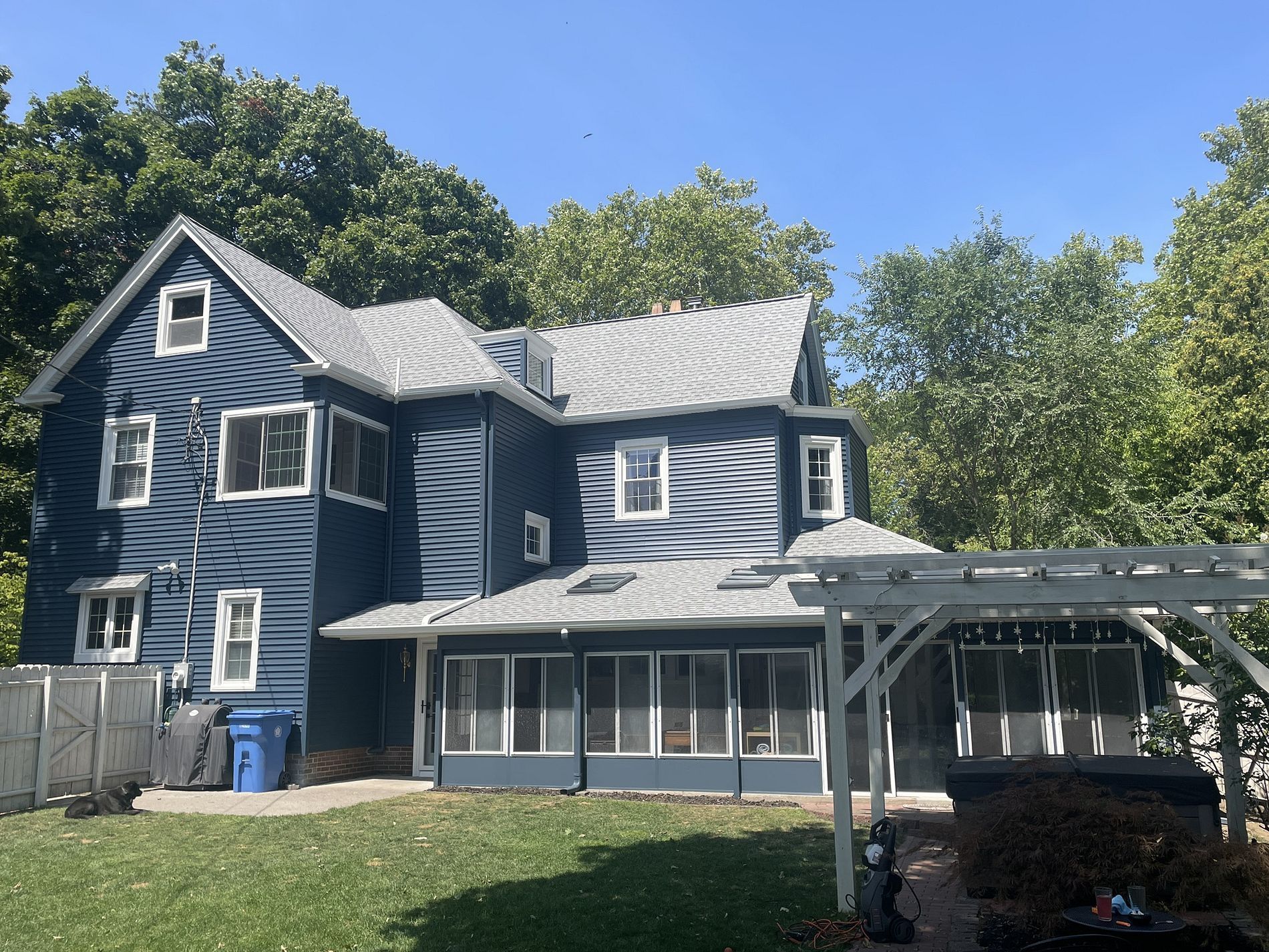 Blue house with white trim, green lawn, and trees in the background.