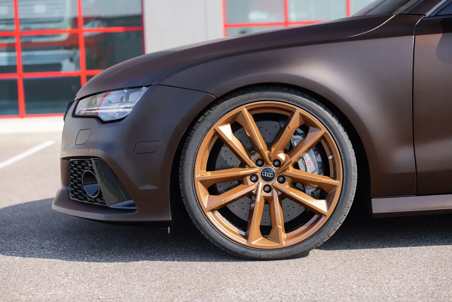 A close up of a brown car with gold wheels.