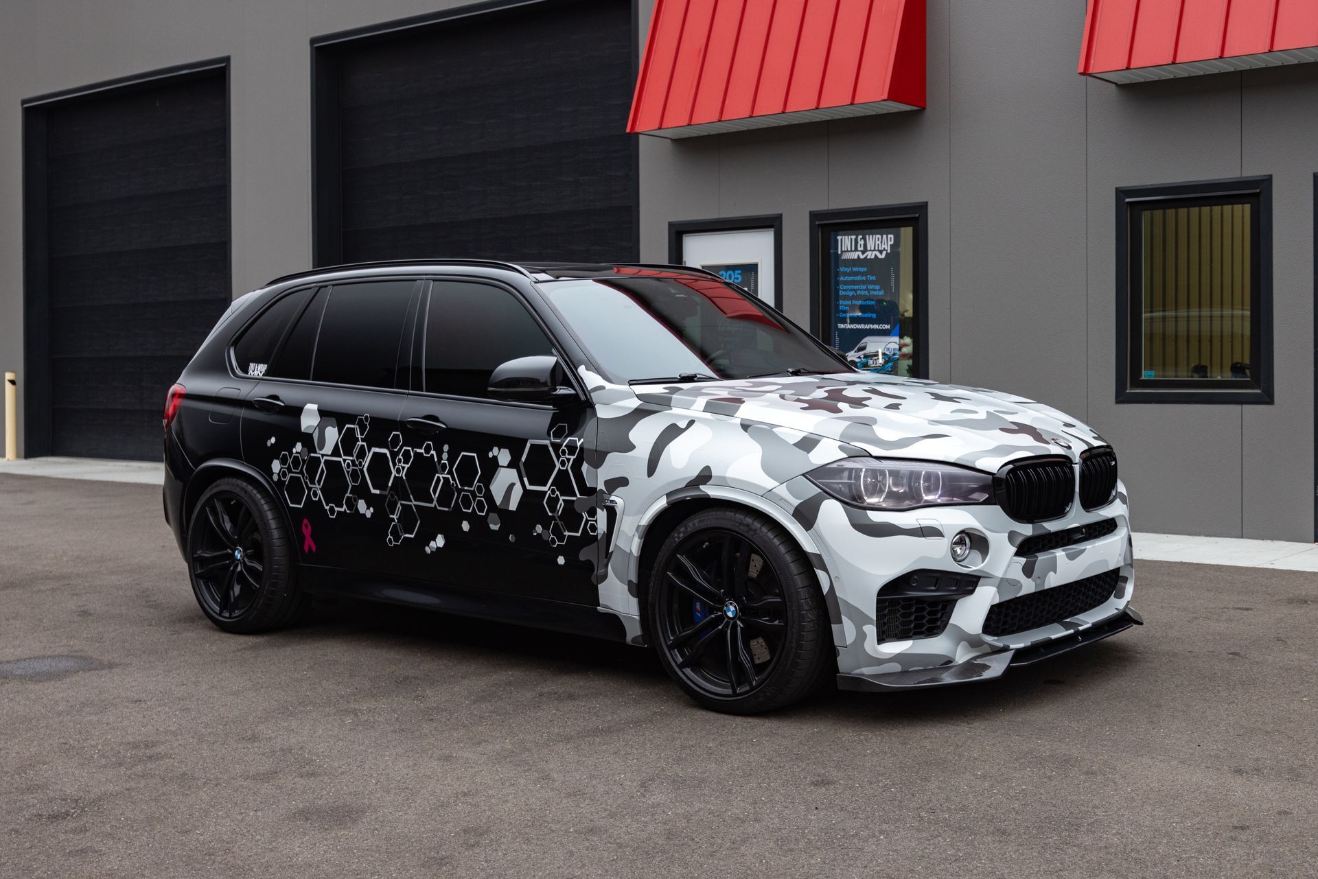 A black and white car is parked in front of a building.