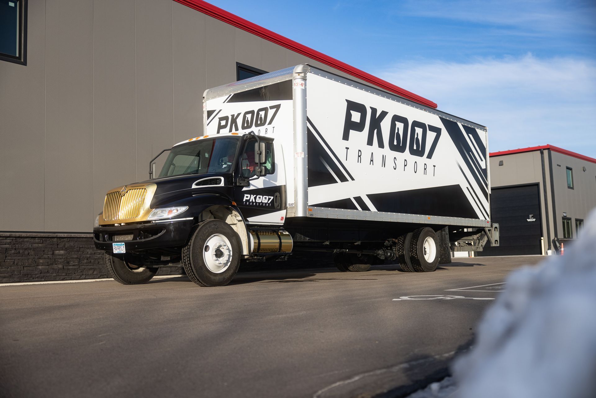 A PK007 truck is parked in front of a building.