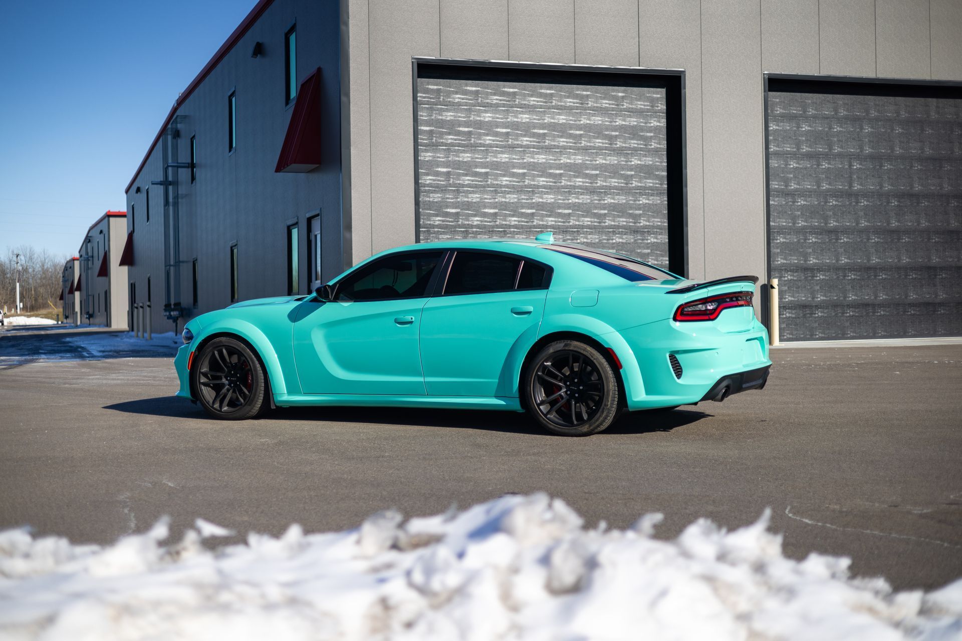 A green Dodge Charger is parked in front of a garage.