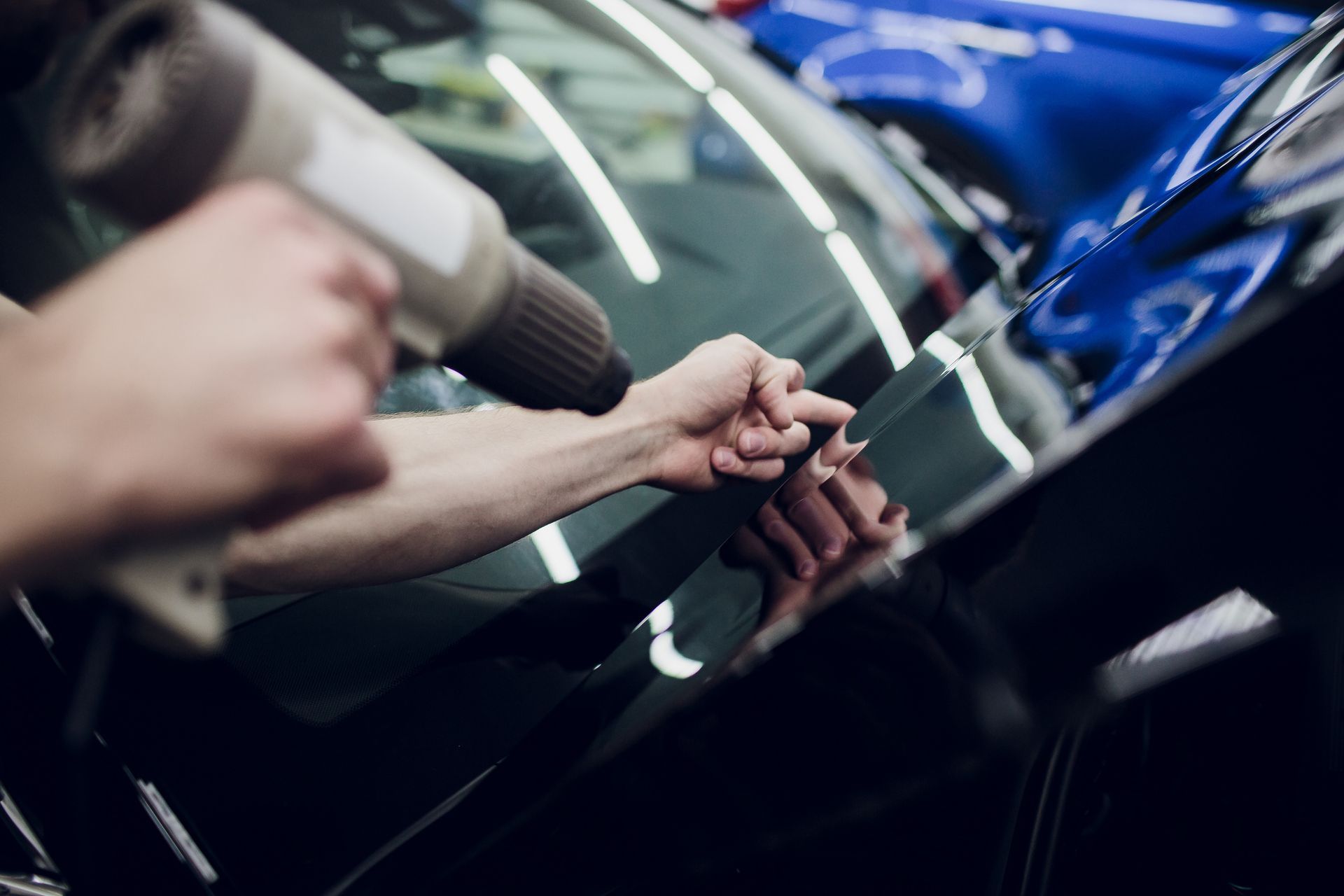 A person is applying tinted glass to a car windshield.