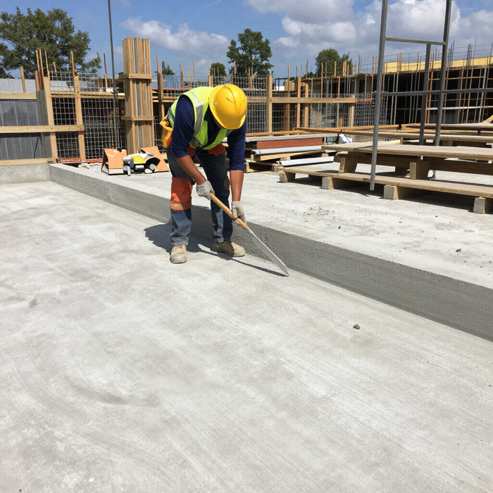 “Worker leveling freshly poured concrete on a large slab for a smooth finish during concrete services in Pine Hills, FL”