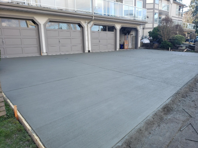 “Wide freshly finished concrete driveway in front of multiple garage doors during concrete services in Pine Hills, FL”