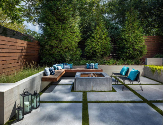 “Modern backyard concrete patio with built-in seating, greenery, and a central fire feature during concrete services in Pine Hills, FL”