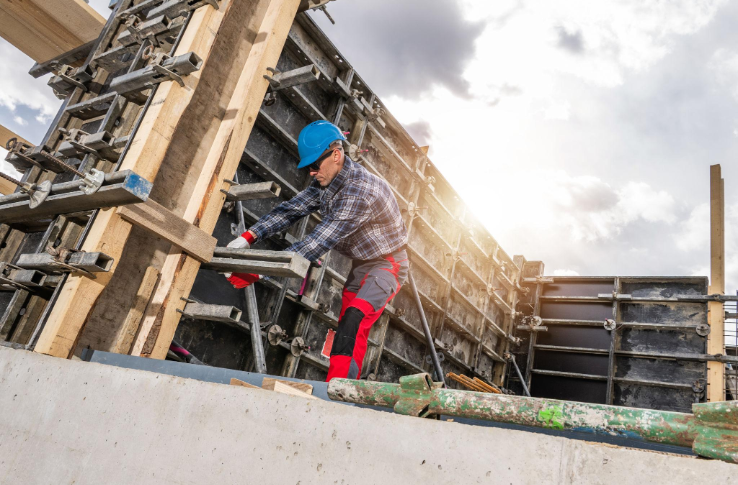 “Worker building a tall concrete wall form with bracing and tools during concrete services in Pine Hills, FL”