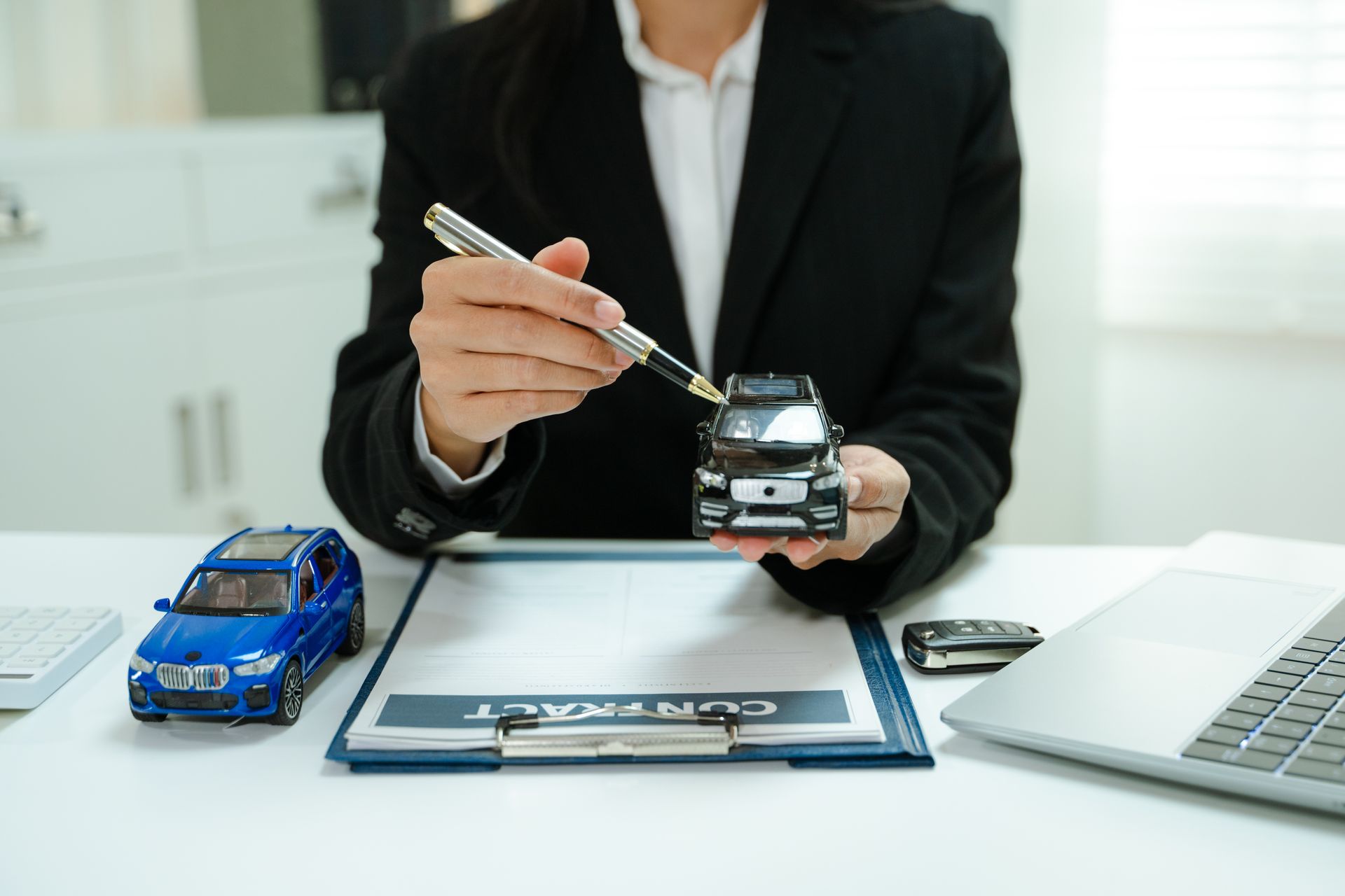 The insurance agent holds a model car over an auto insurance contract.
