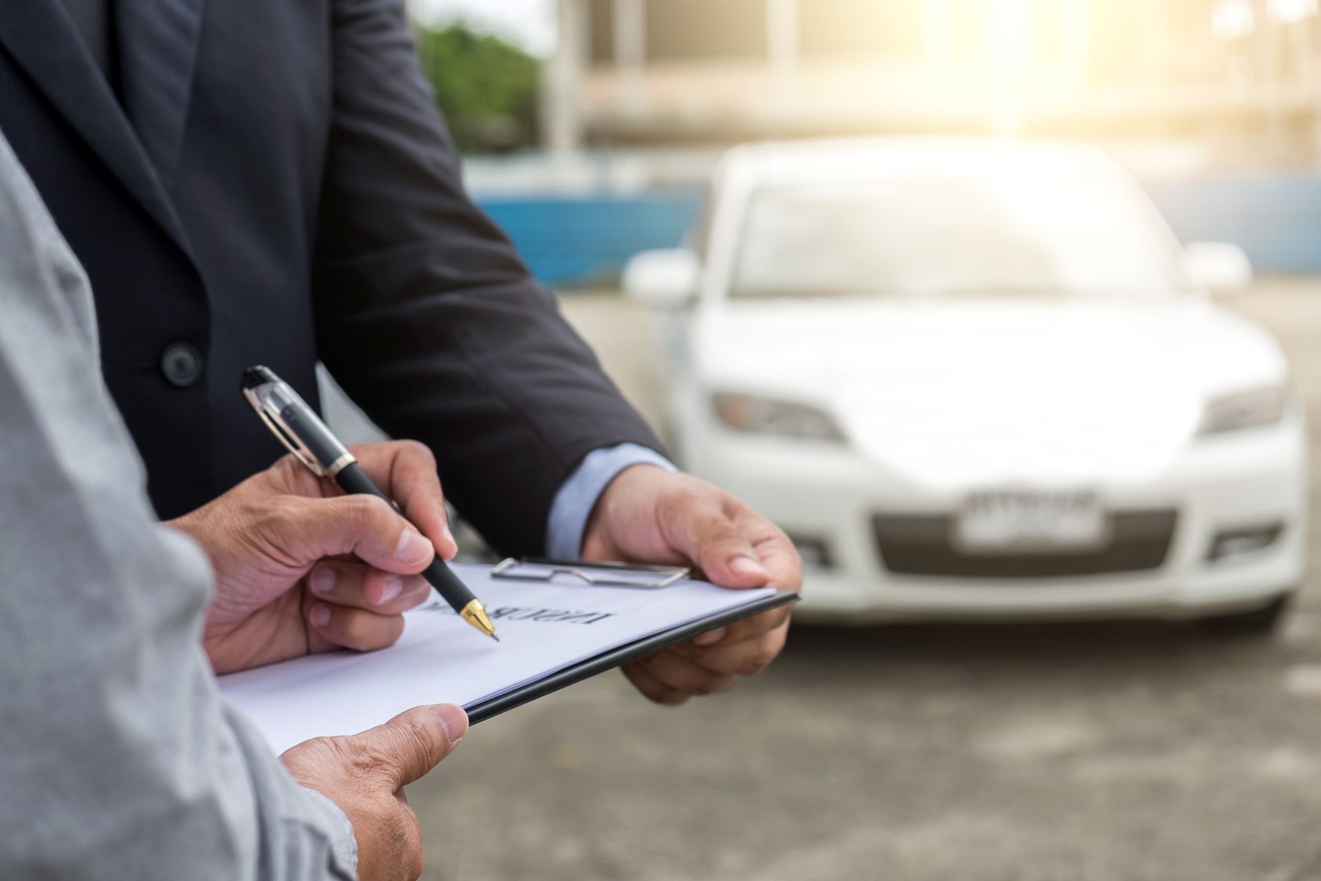 Agent evaluates damaged vehicle, highlighting vehicle insurance services as client signs docs.