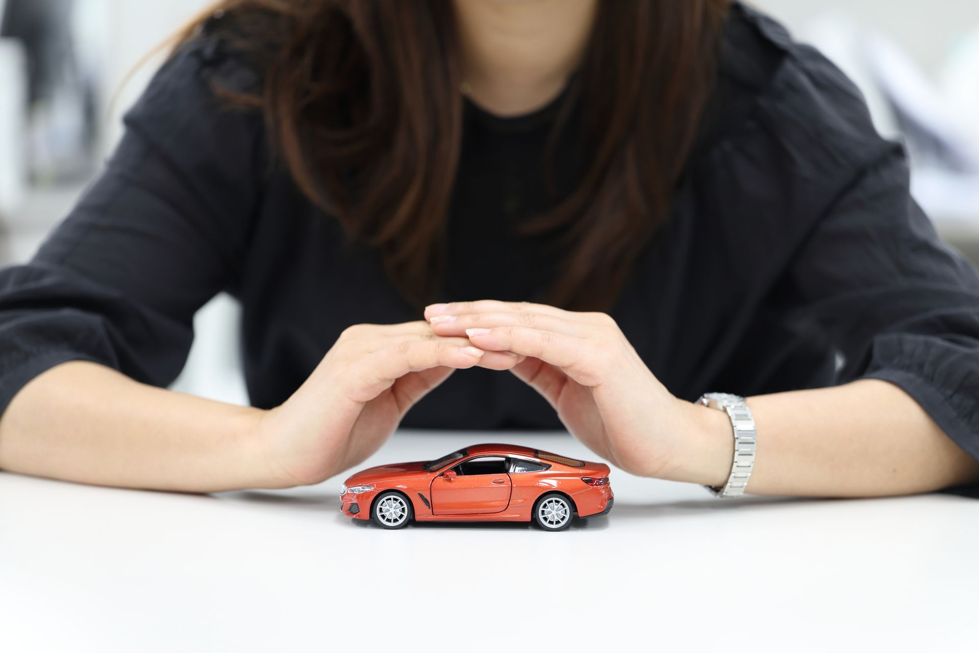 Hands protecting a car model.