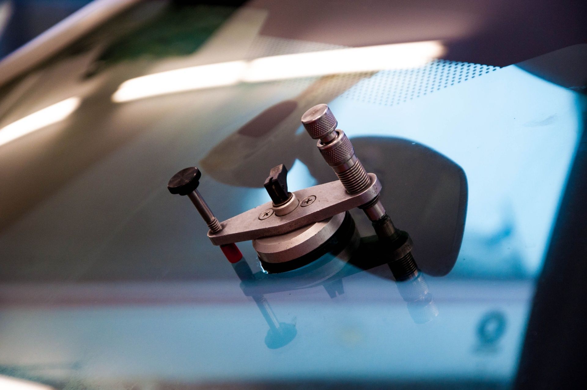Close-up of a small device mounted on a car windshield, with a blue sky reflection in the glass