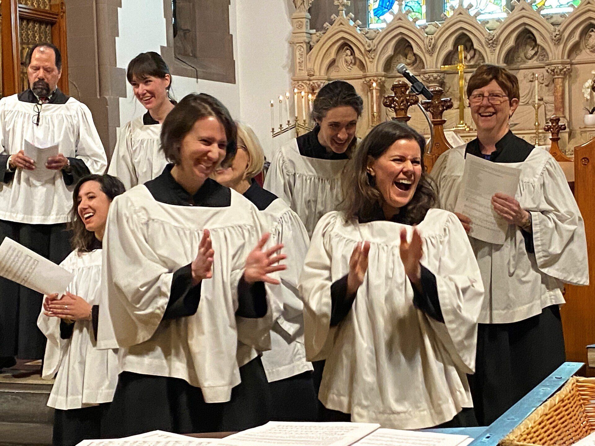 A group of women in choir uniforms are singing in a church.