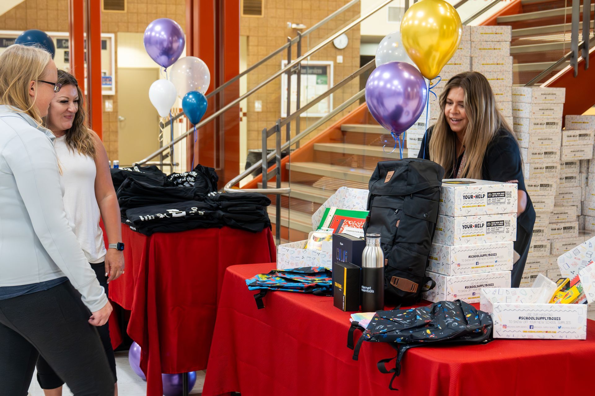 A group of women are standing around a table with balloons on it.