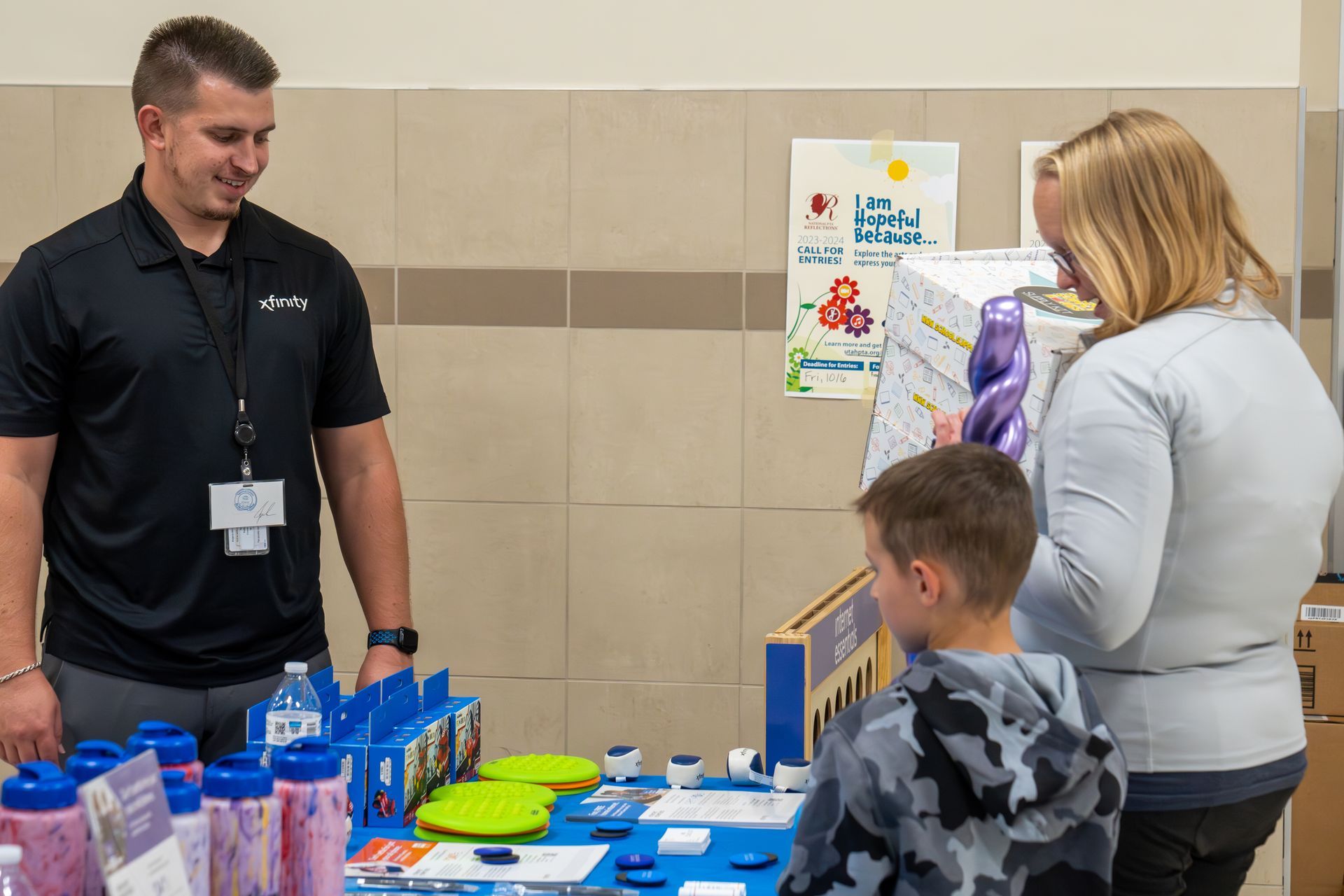 A man and a woman are standing next to a boy sitting at a table.