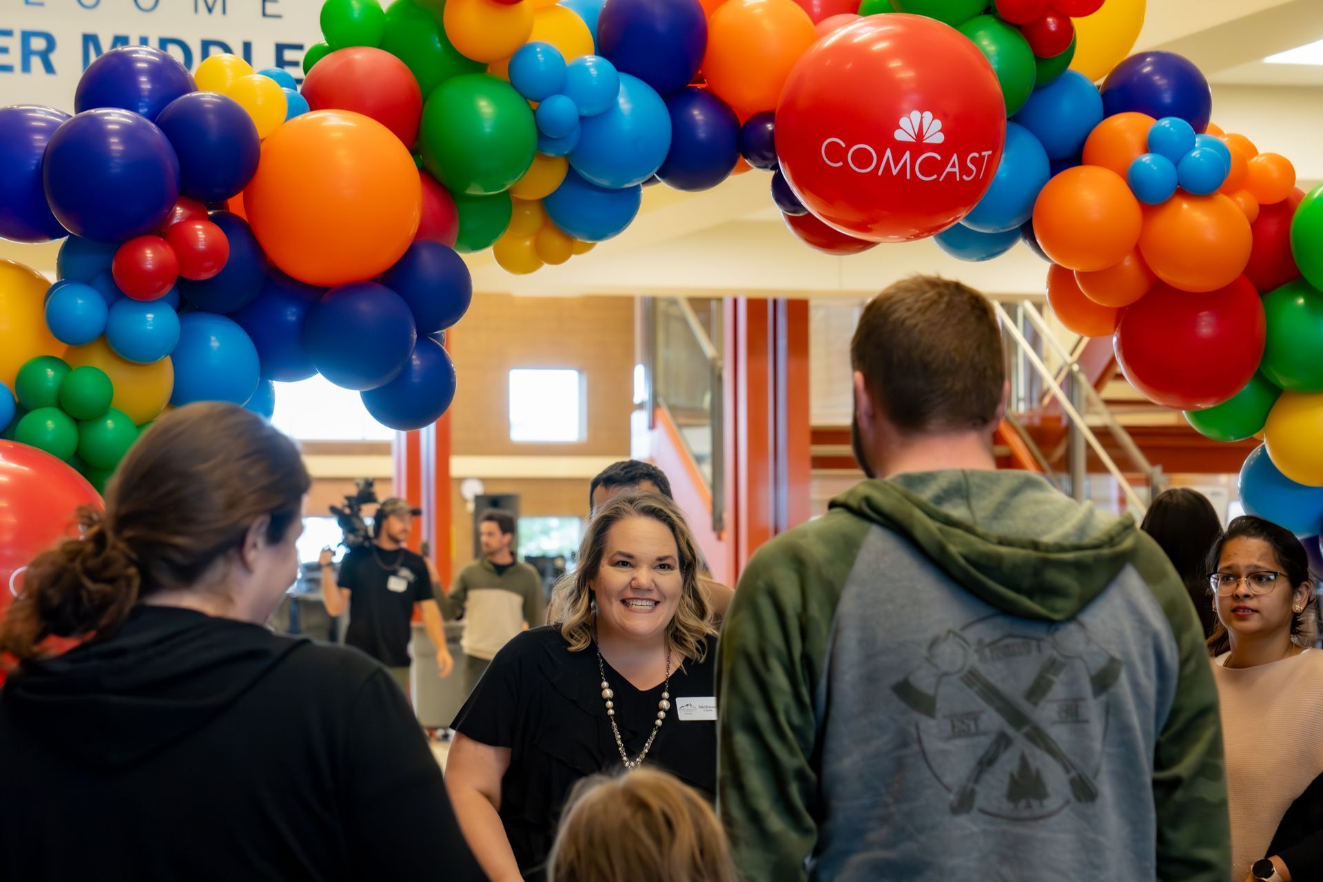 A group of people standing under a comcast balloon