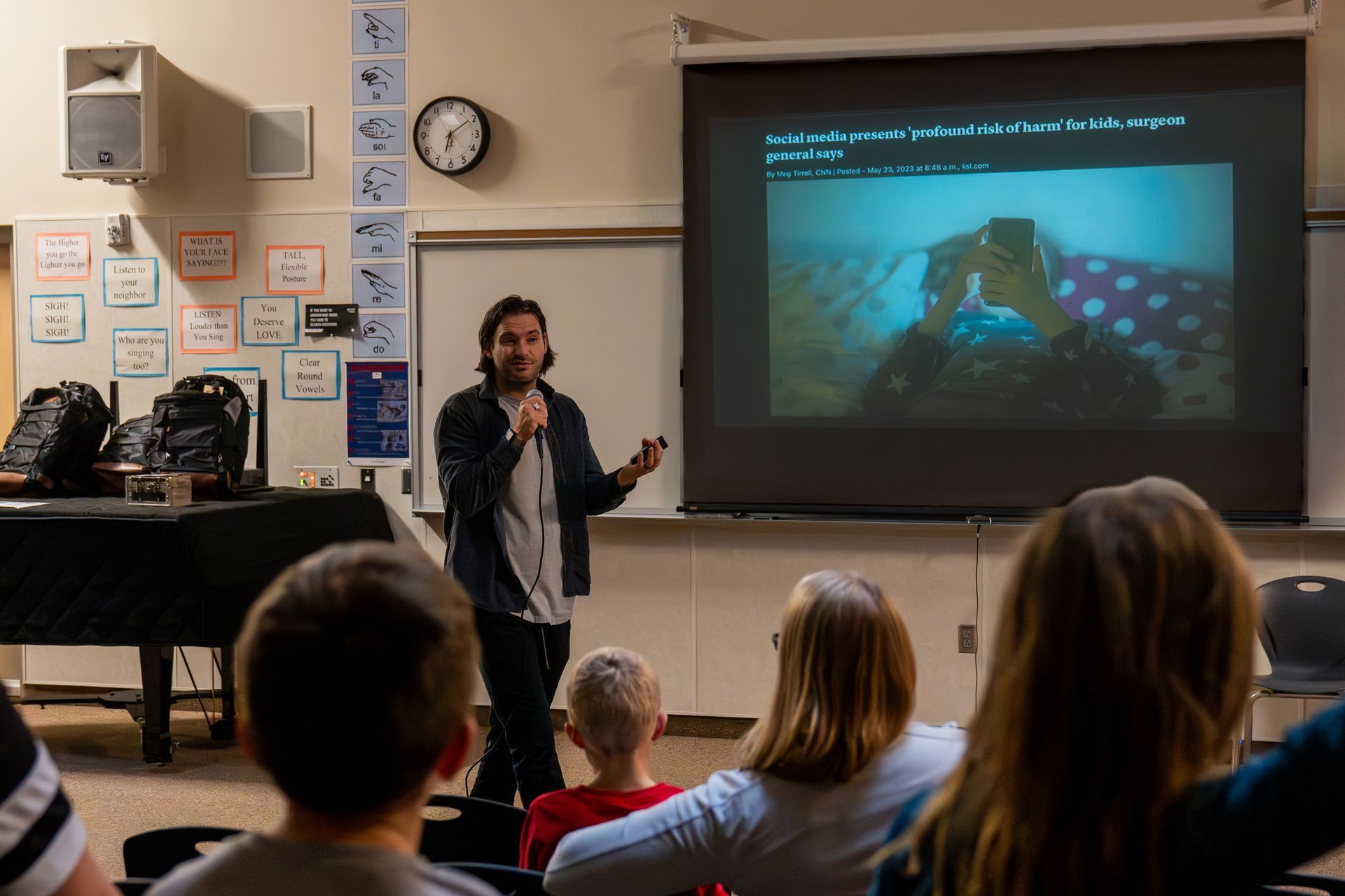 A man is giving a presentation to a group of children in a classroom.