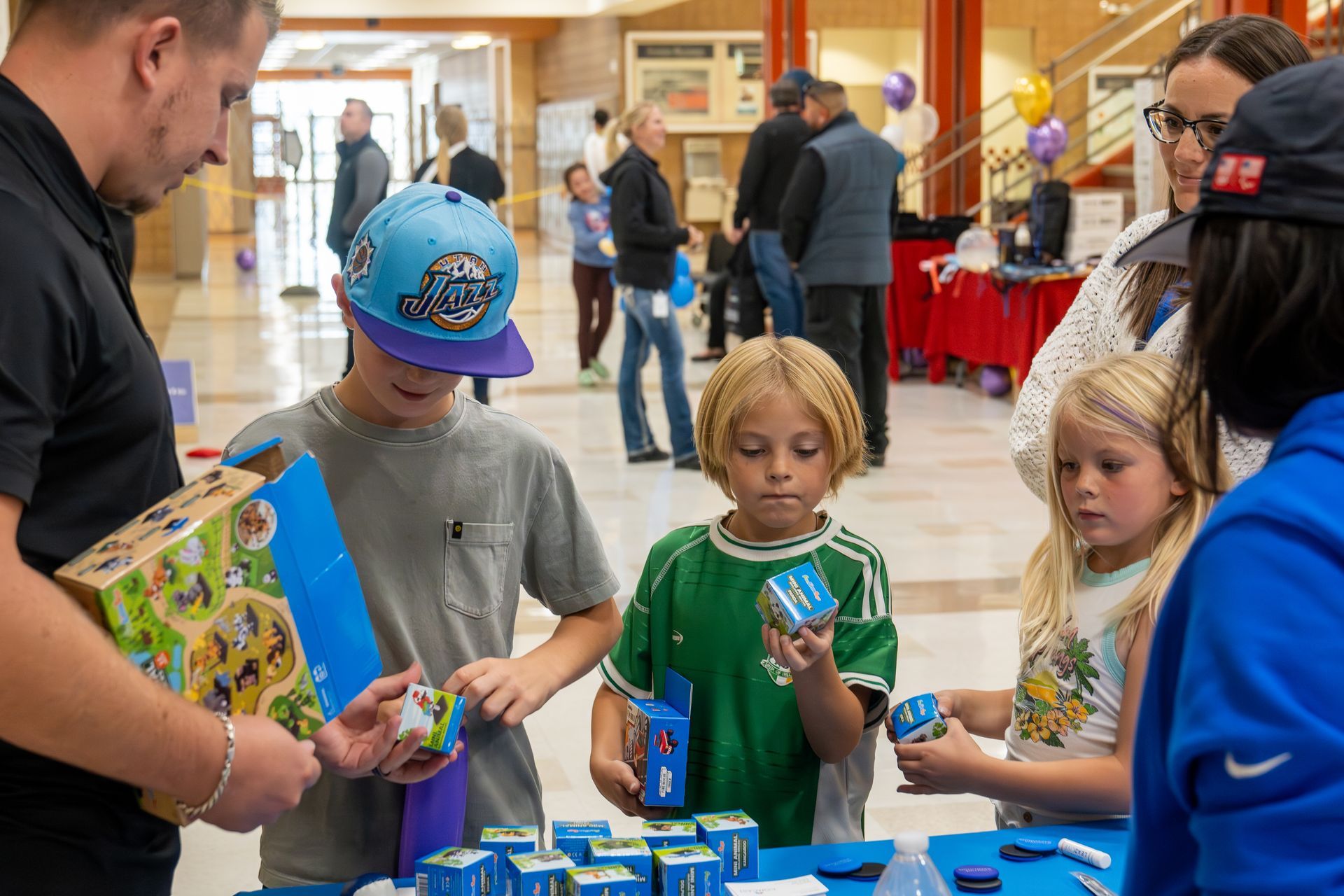A group of children are standing around a table looking at toys.