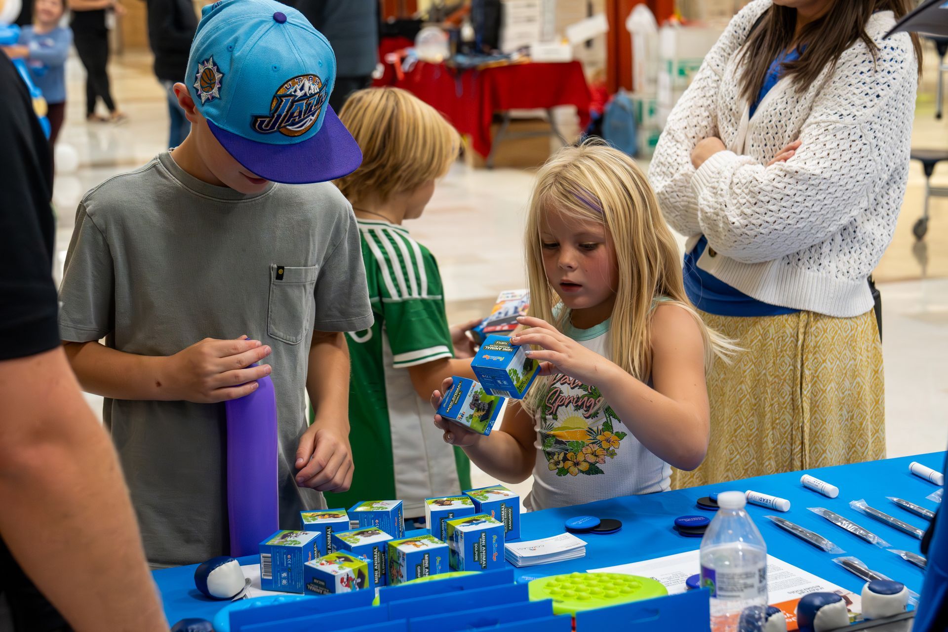 A group of children are standing around a table playing with toys.