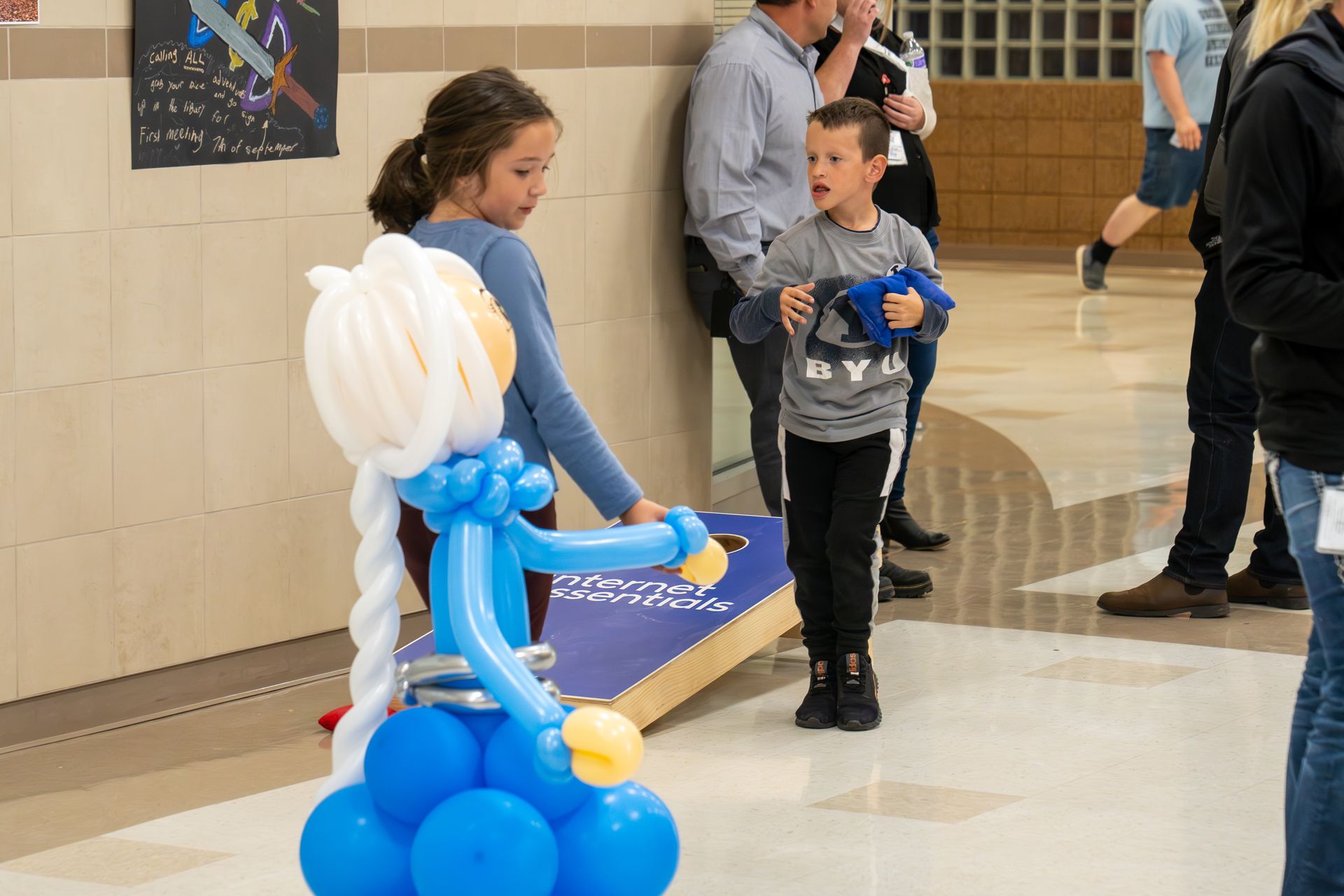 A girl and a boy are standing next to a balloon sculpture of elsa from frozen.