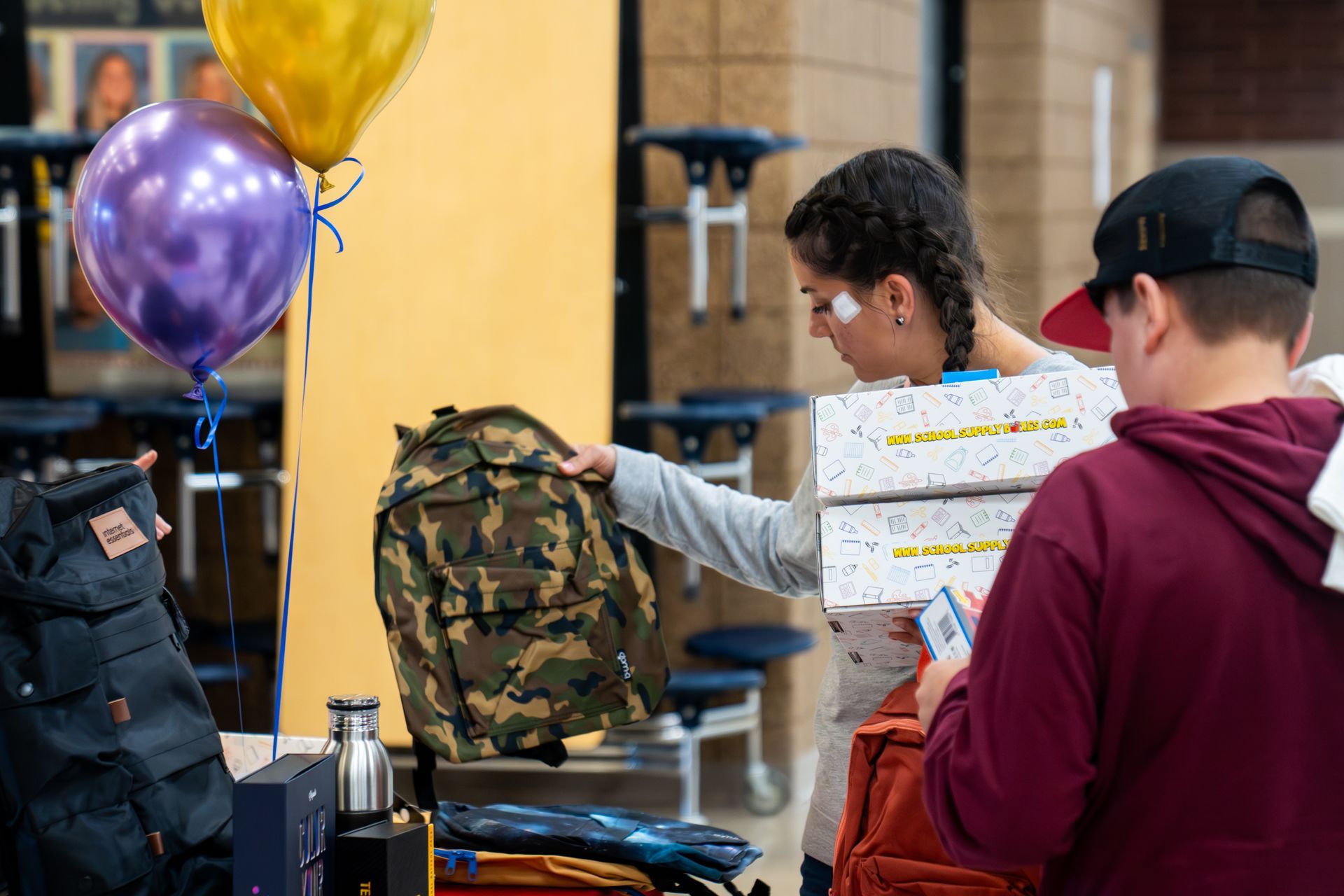 A group of people are standing around a table with backpacks and balloons.