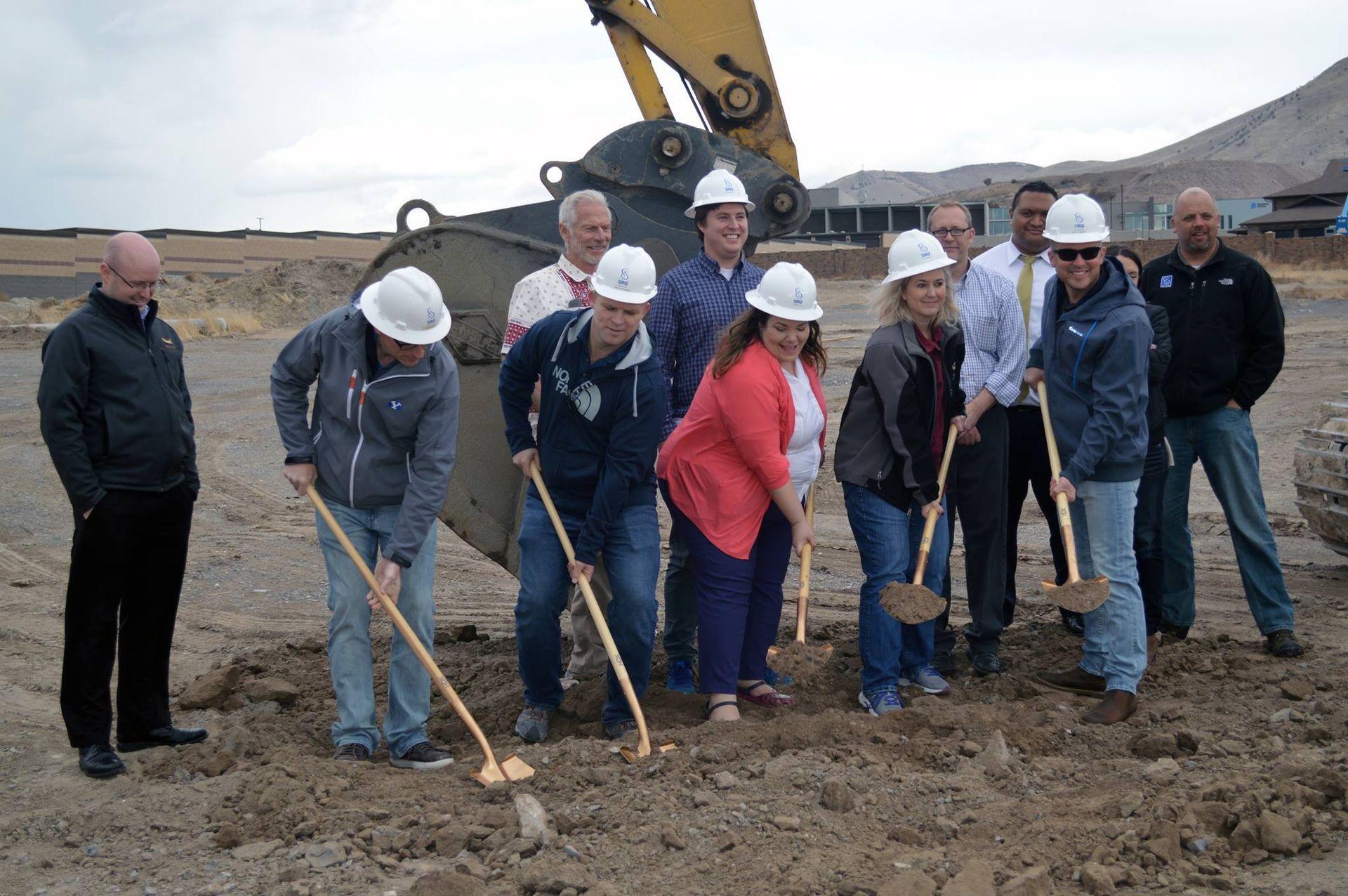 A group of people wearing hard hats are digging in the dirt