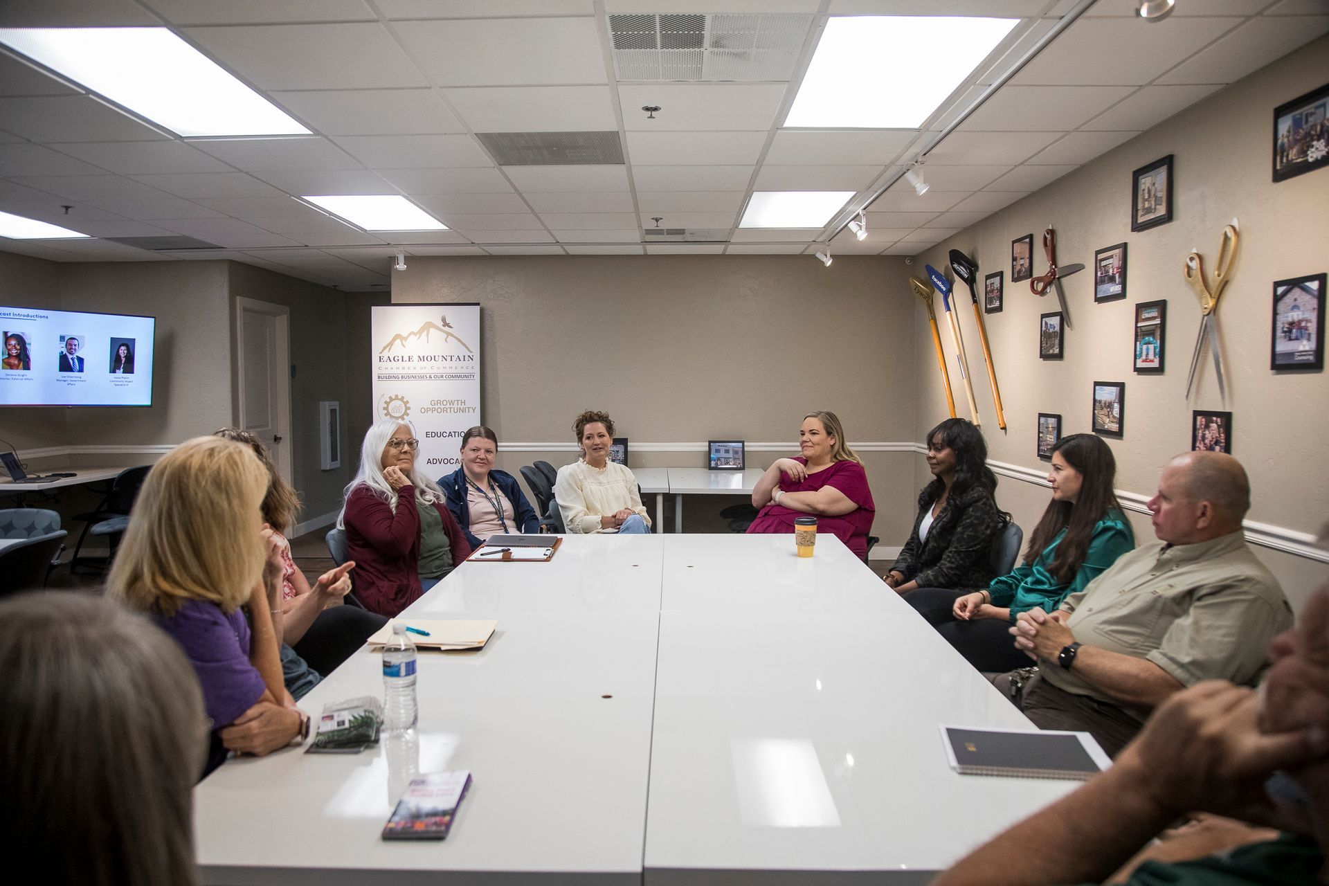 A group of people are sitting around a long table in a room.