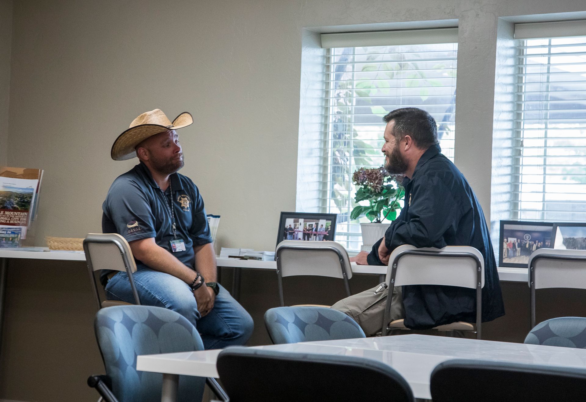 Two men are sitting at a table talking to each other.