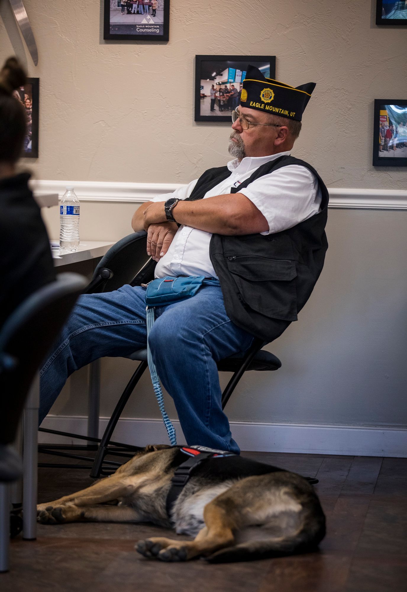 A man is sitting in a chair with a dog laying on the floor.