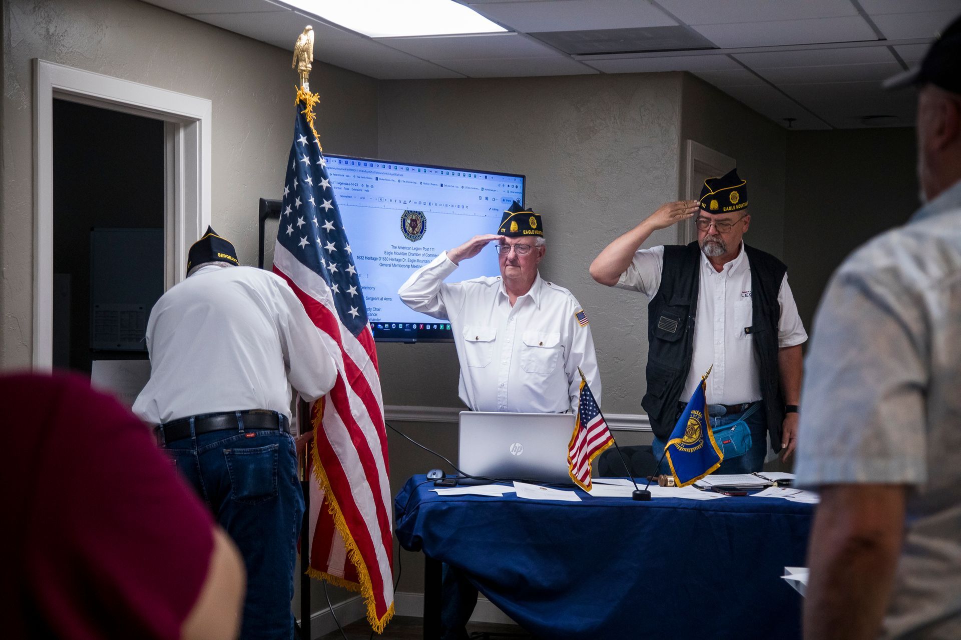 A group of men are saluting in front of an american flag.