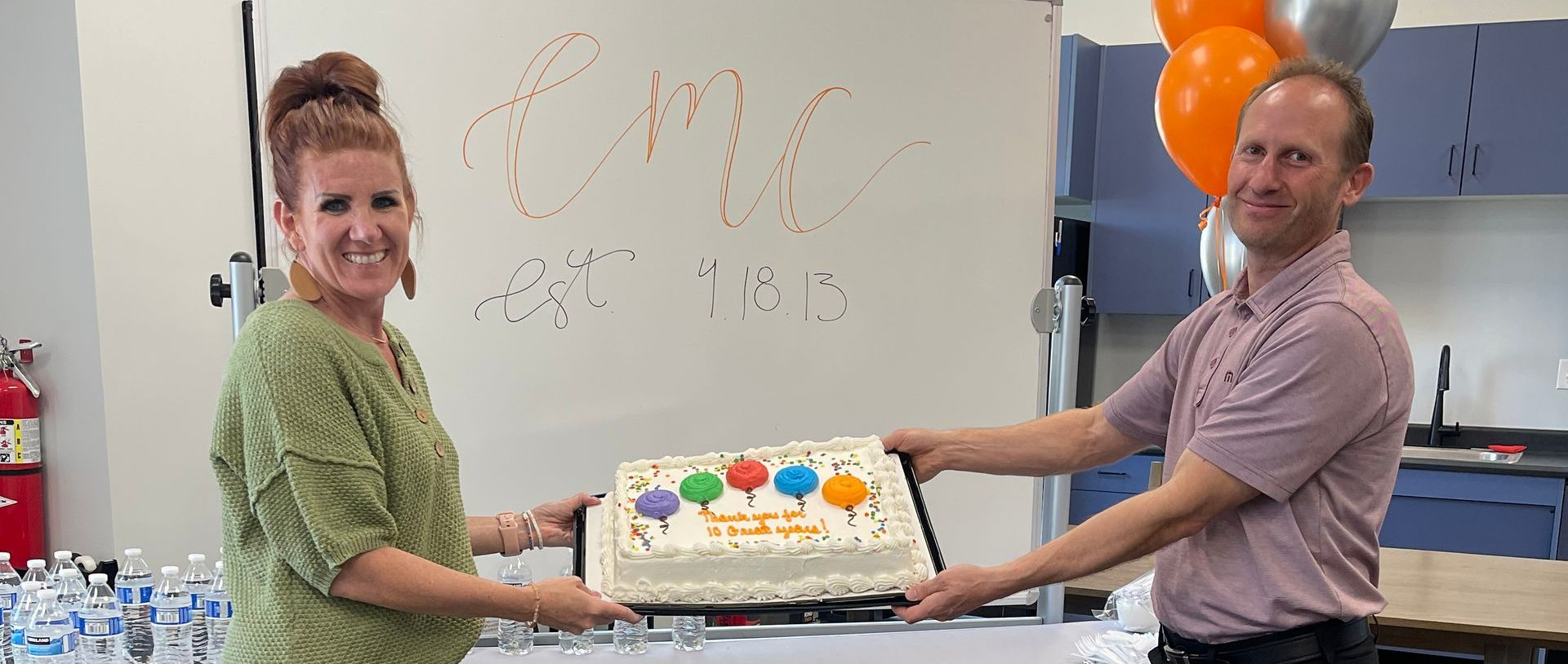 A man and a woman are holding a cake in their hands.