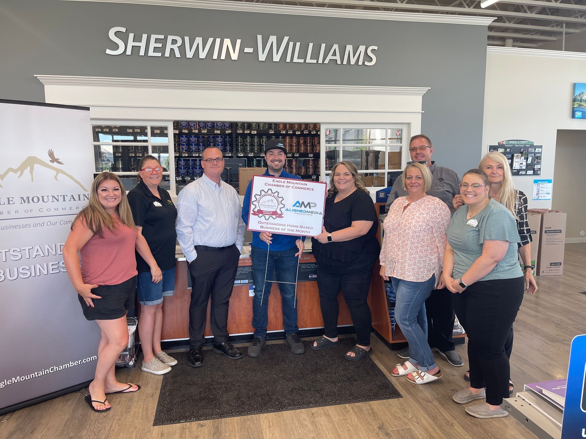 A group of people are standing in front of a sherwin williams store.