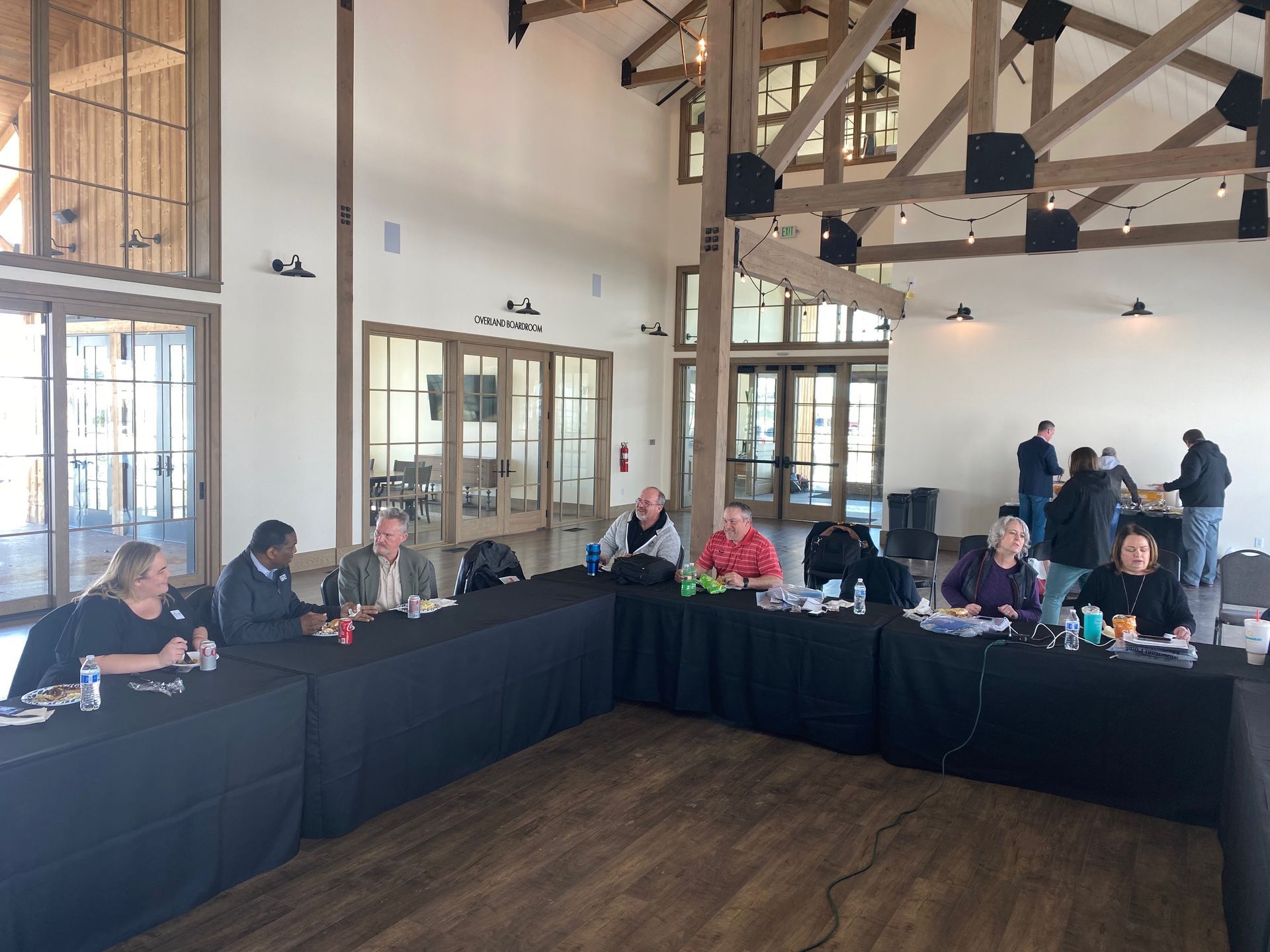 A group of people are sitting at long tables in a room.