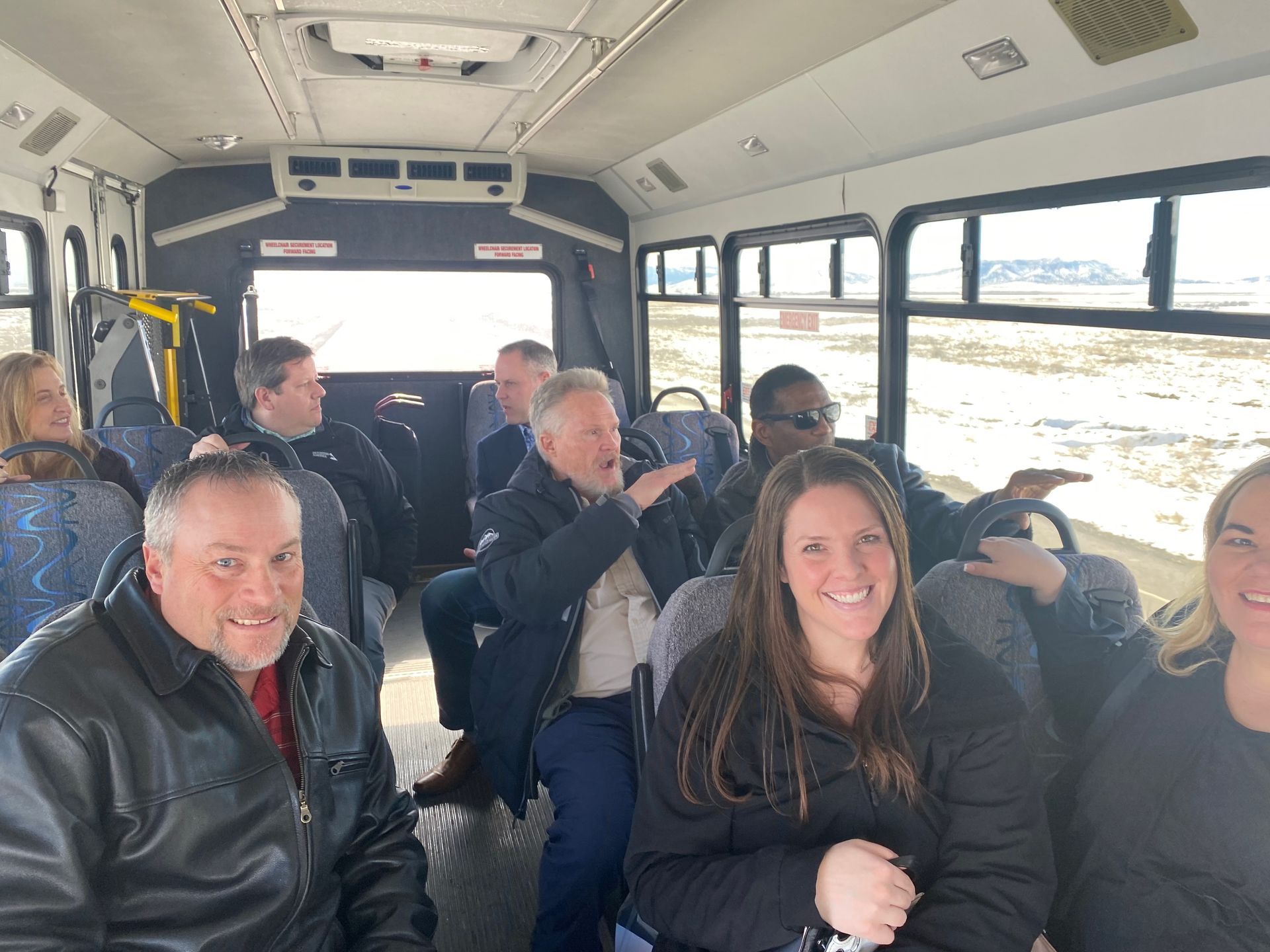 A group of people are sitting on a bus and smiling.