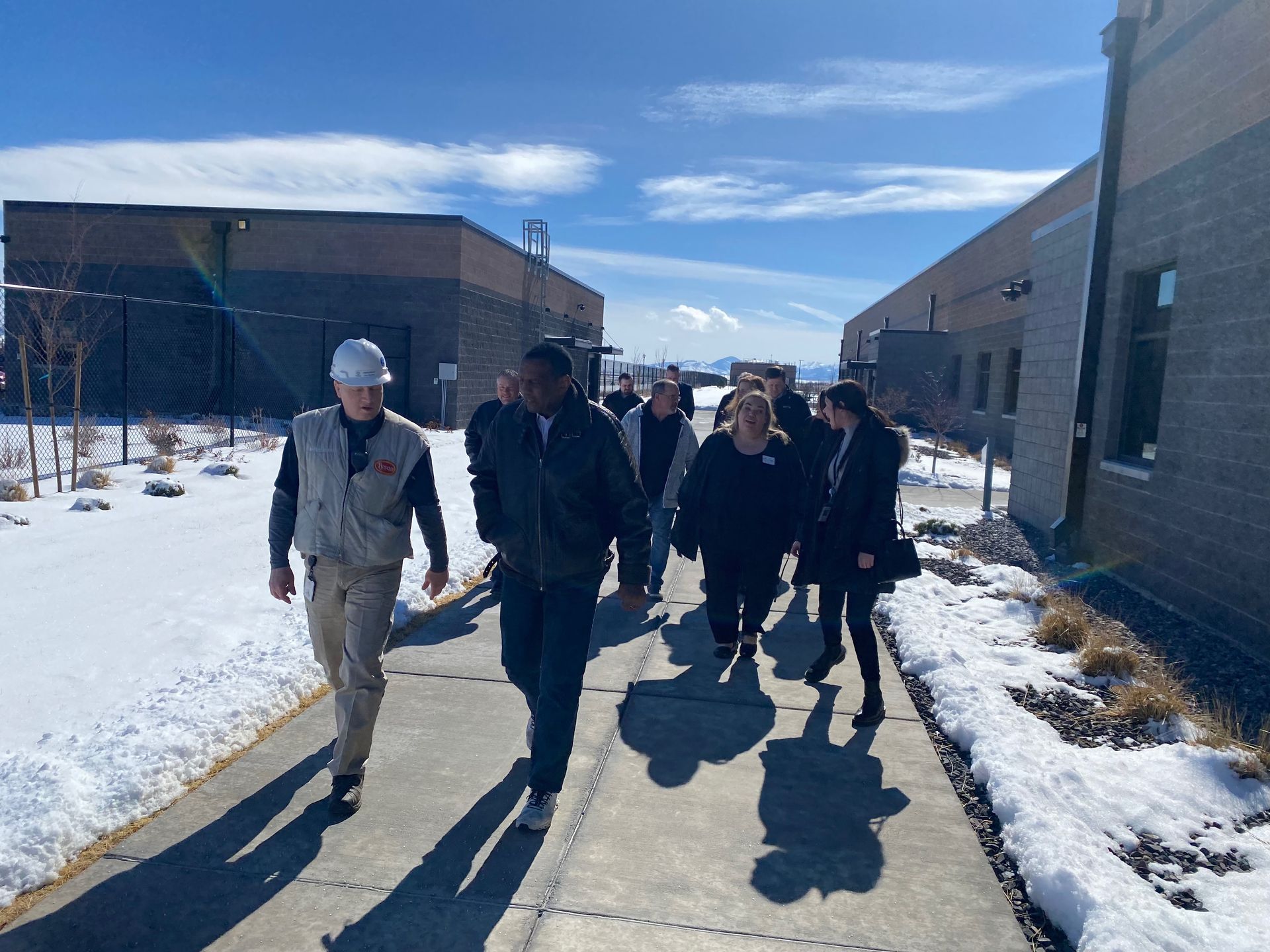 A group of people are walking down a sidewalk in the snow.
