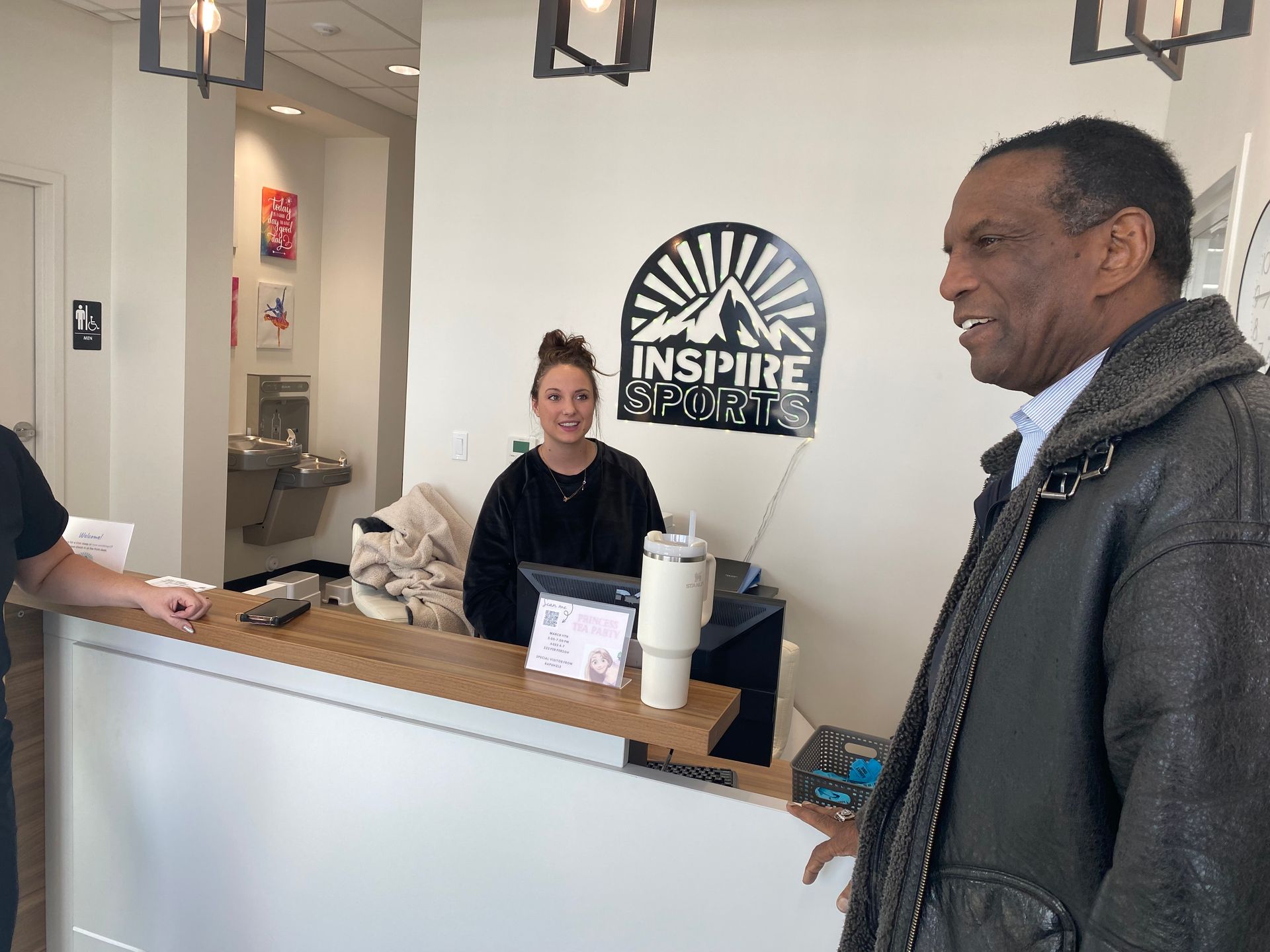 A man and a woman are standing in front of a reception desk.
