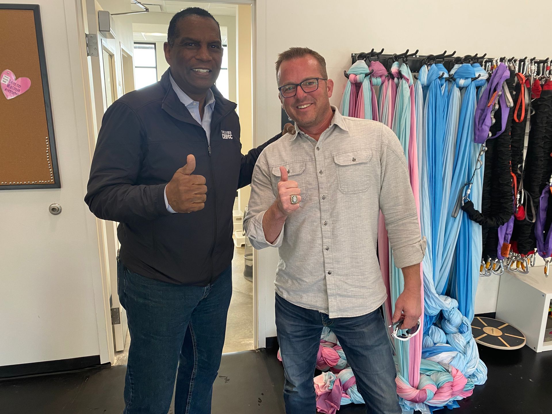 Two men are posing for a picture and one is giving a thumbs up