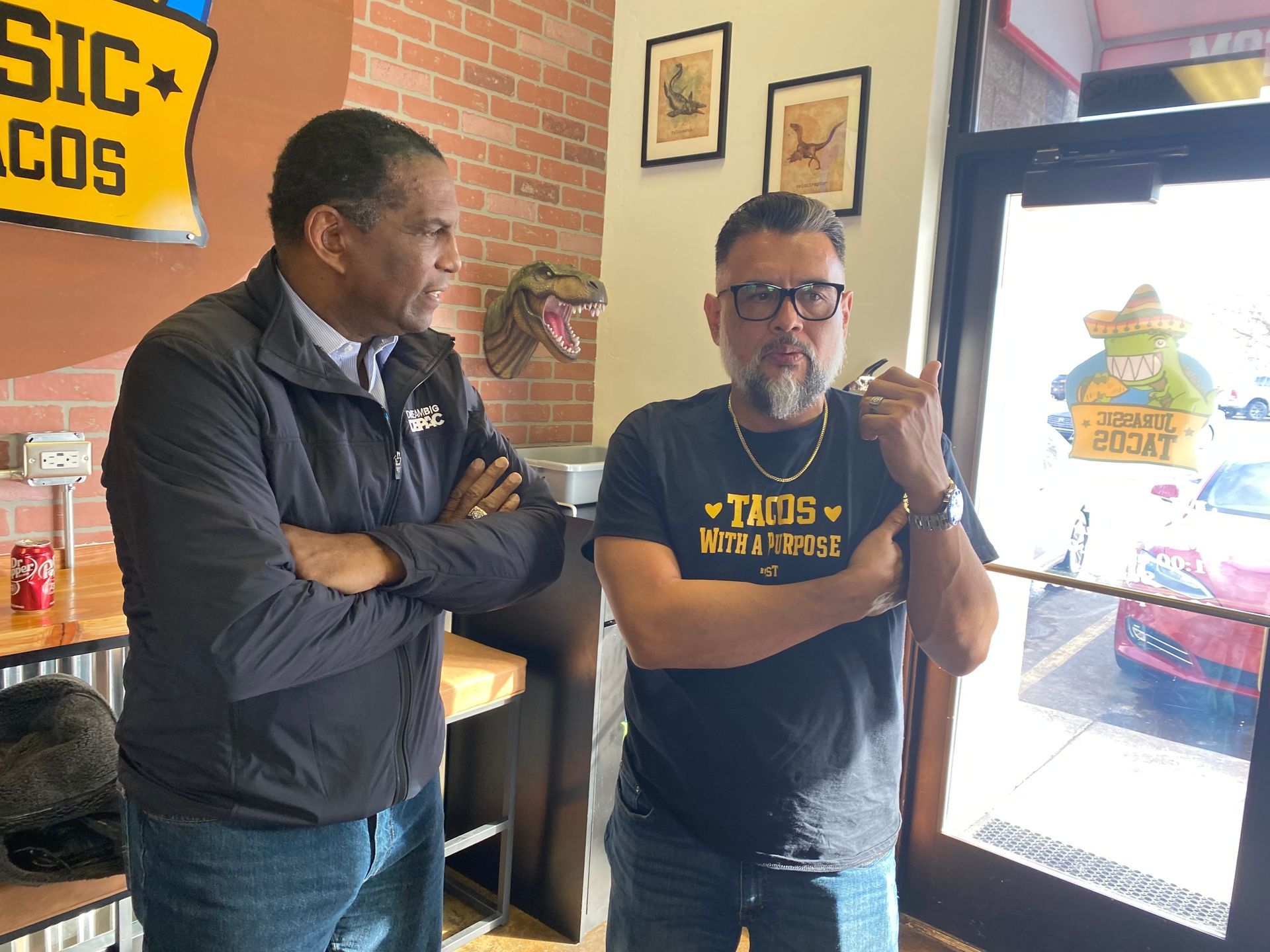 Two men are standing next to each other in a restaurant.