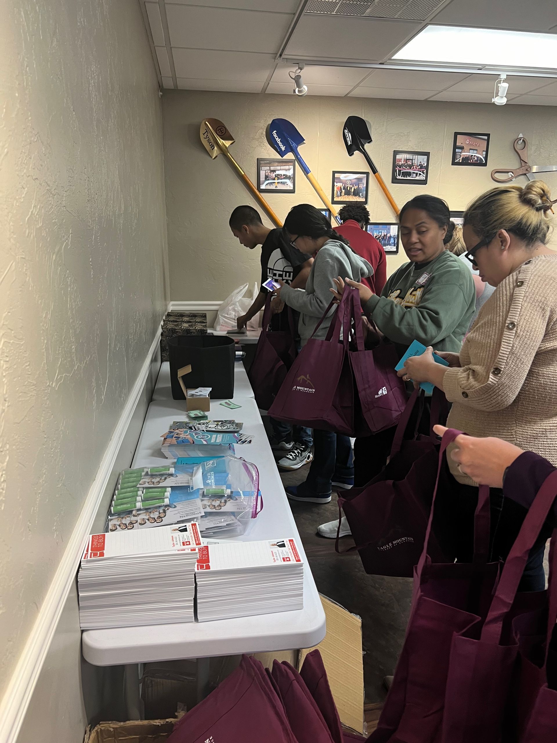 A group of people are standing around a table looking at bags.