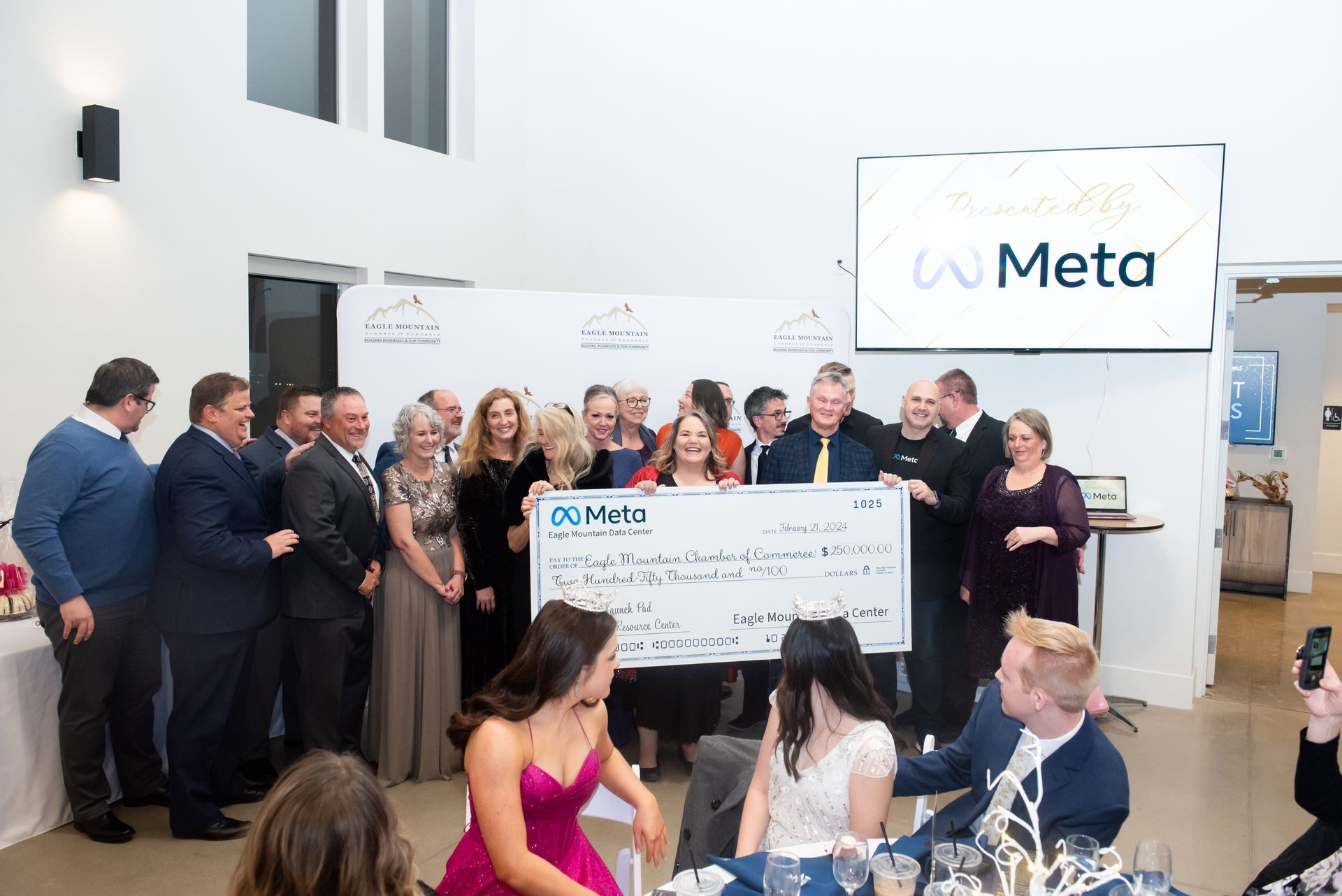 A group of people are standing around a table holding a large check.