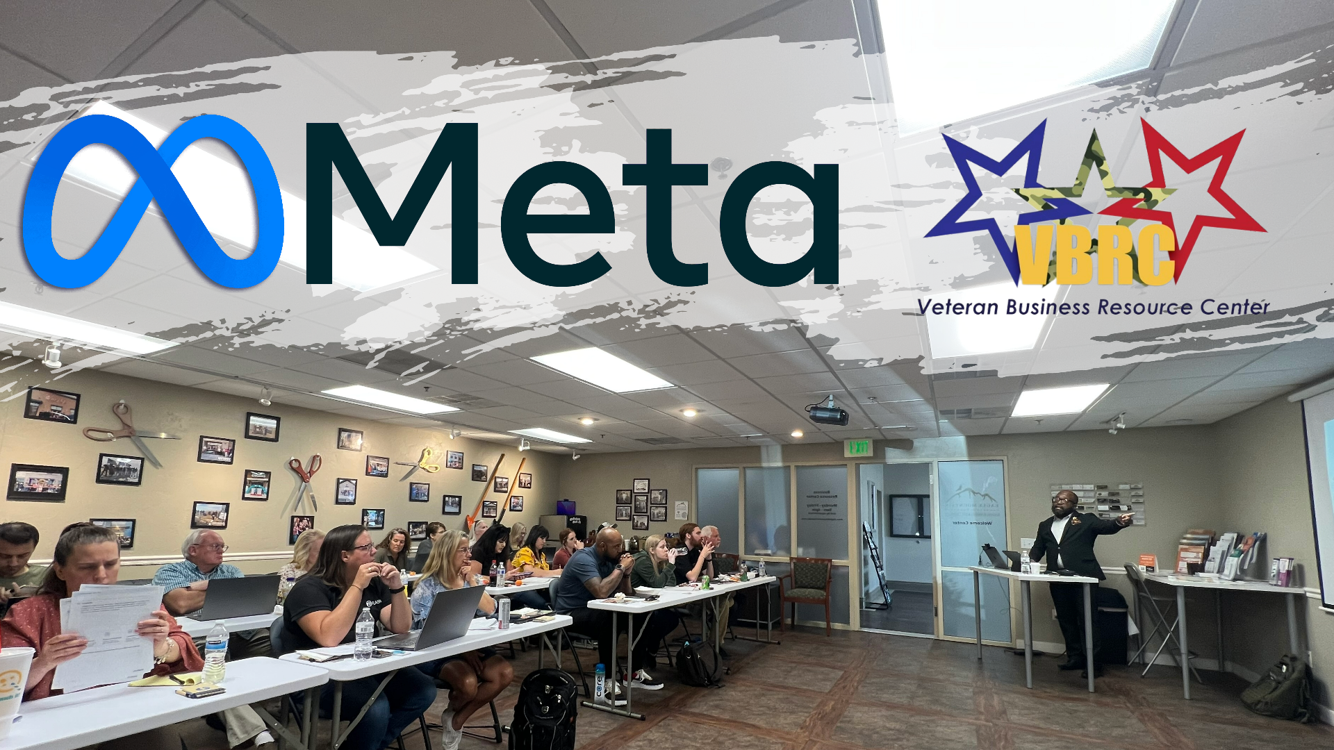 A group of people are sitting at tables in a room with a meta logo in the background.