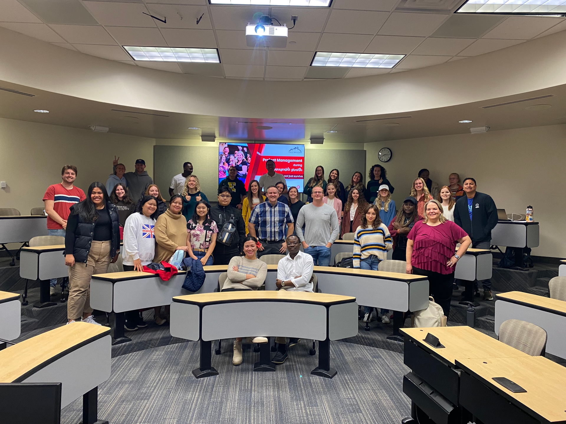 A group of people are posing for a picture in a classroom.