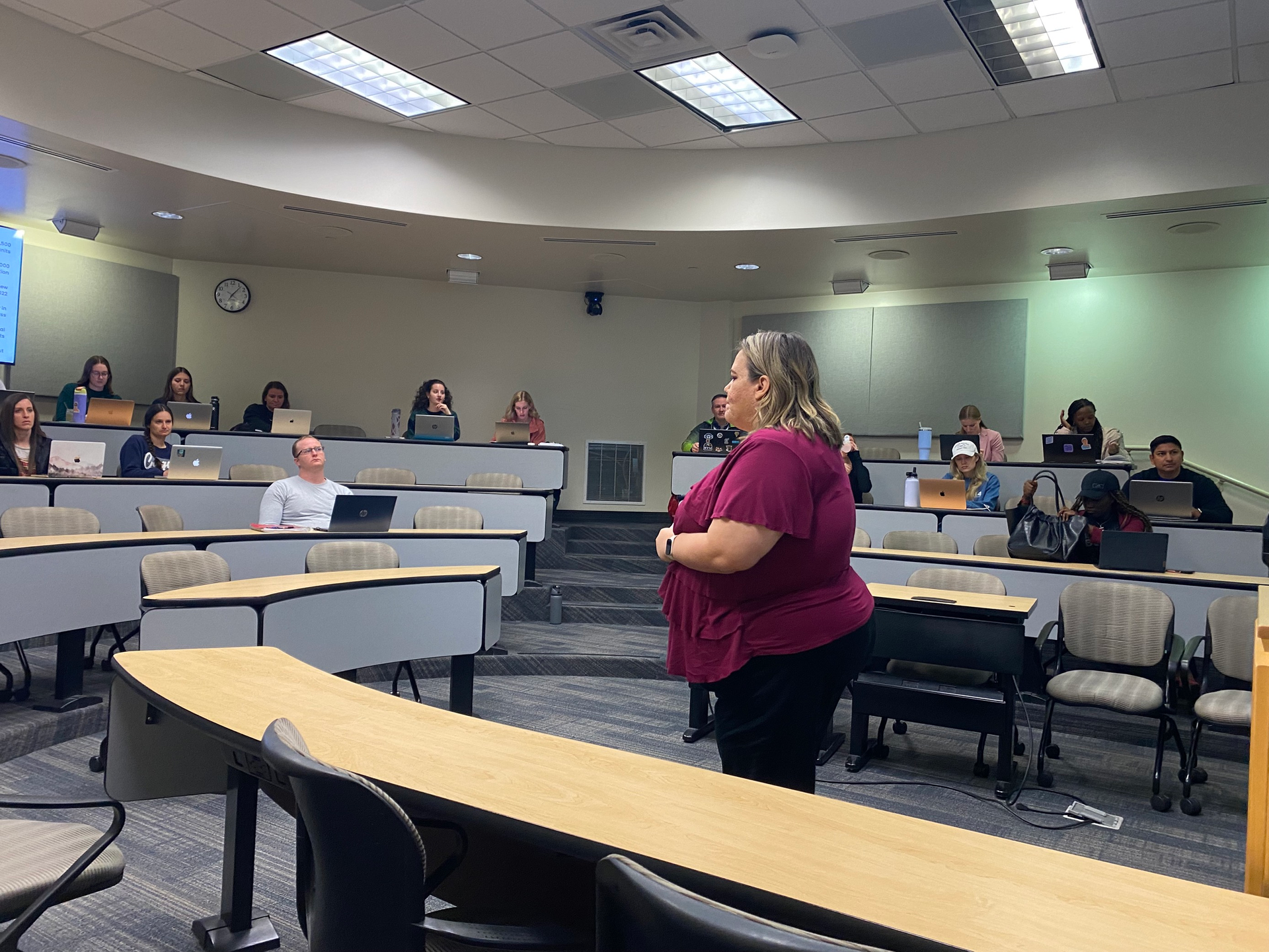 A woman is standing in front of a classroom full of people.