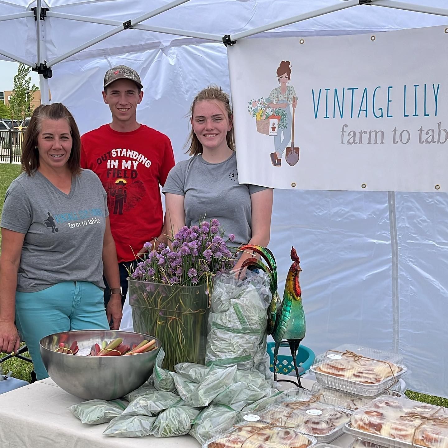 A group of people standing in front of a vintage lily farm to table
