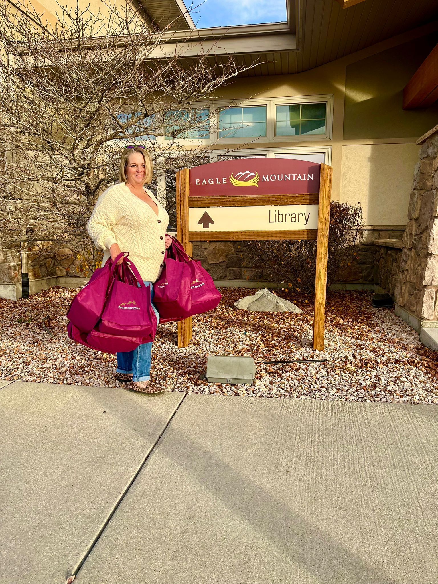 A woman is standing in front of a building holding purple bags.