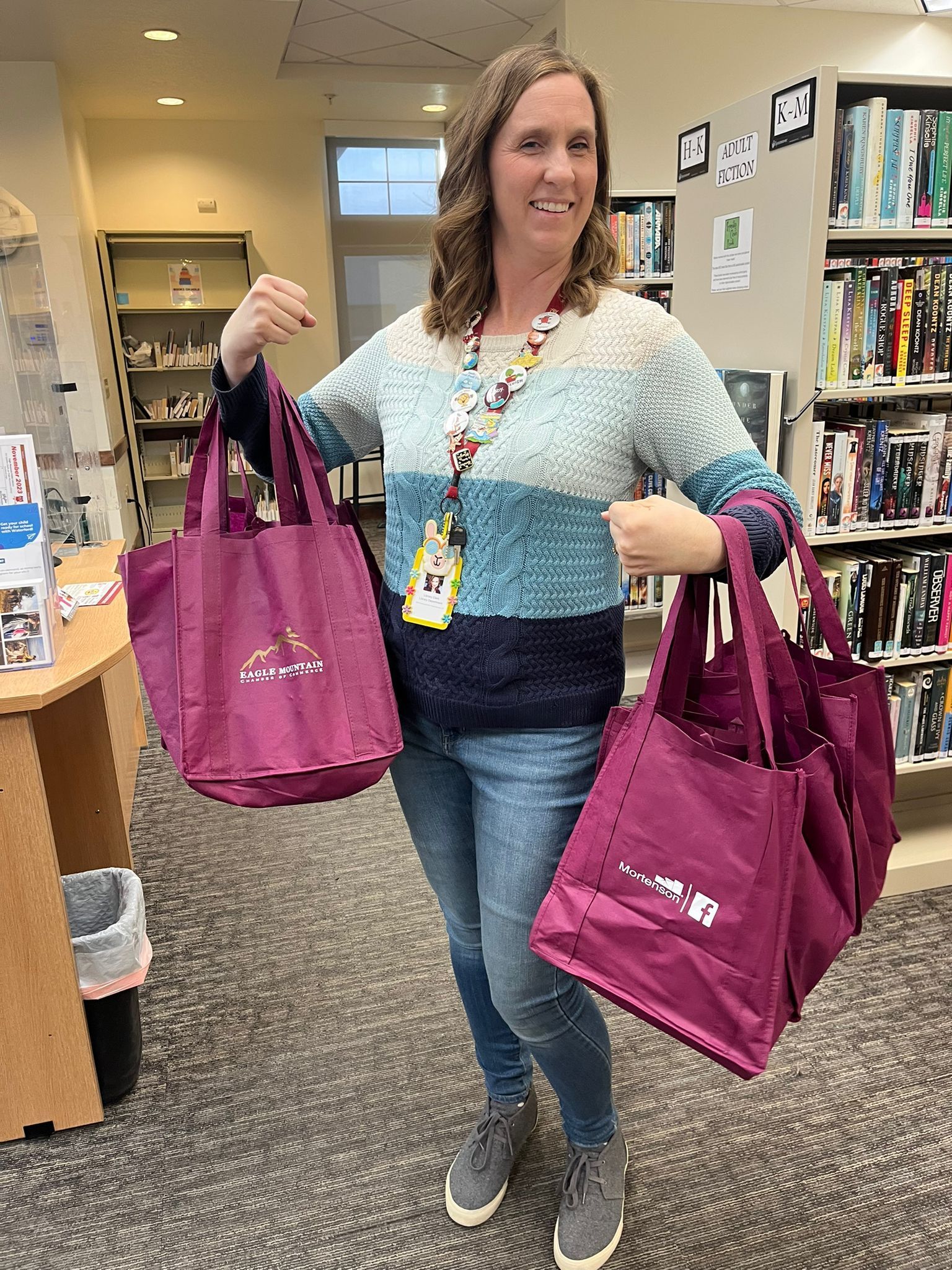 A woman is holding two purple bags in a library.
