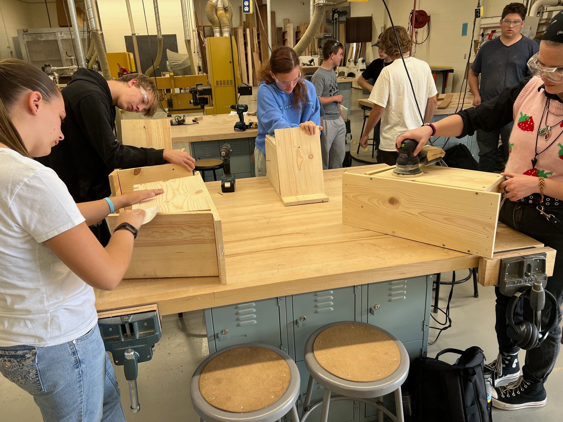 A group of people are working on wooden boxes in a workshop.