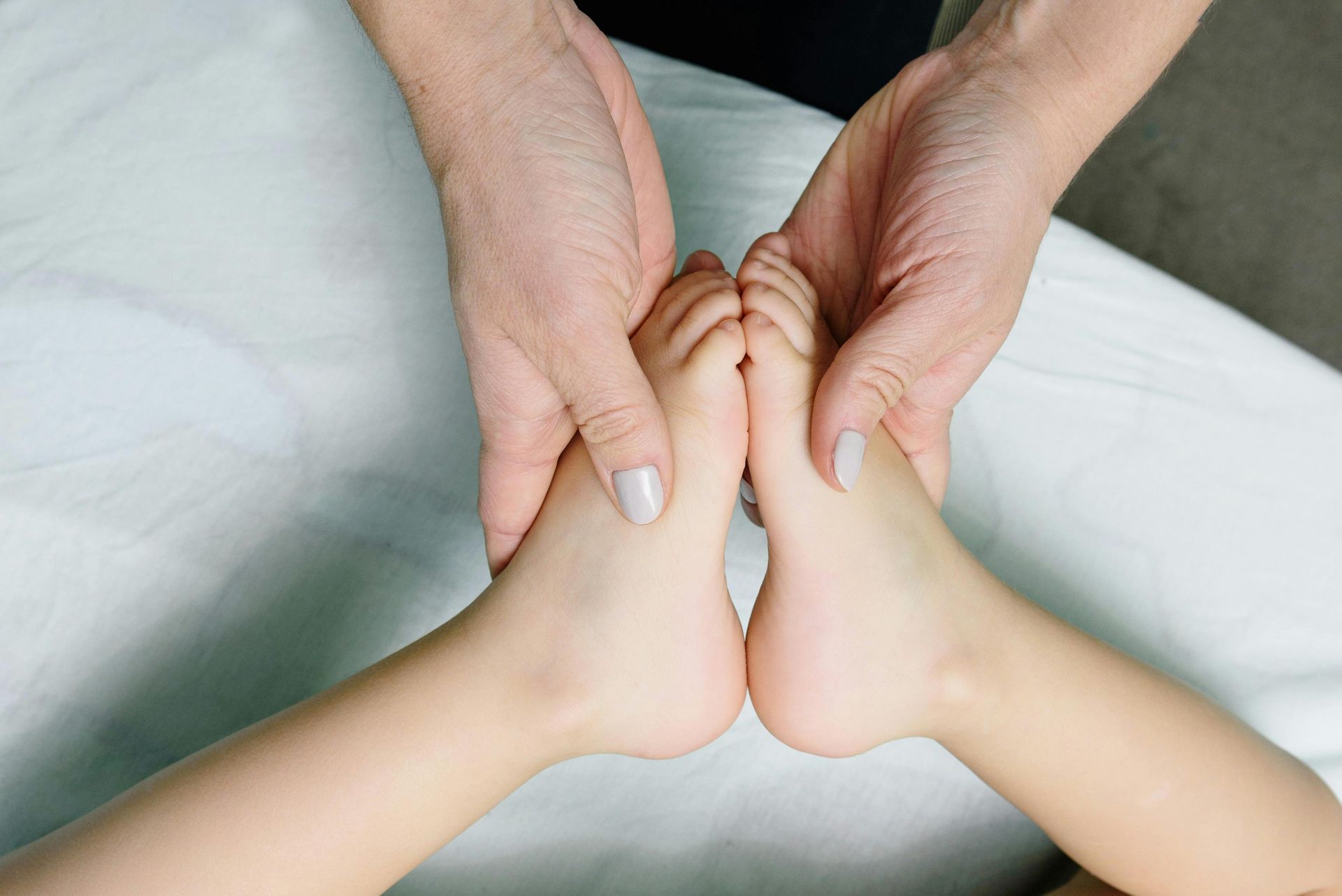 A person is giving a child a foot massage.