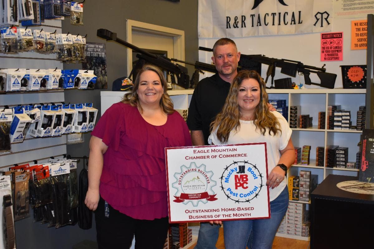 A man and two women are standing in a store holding a sign.
