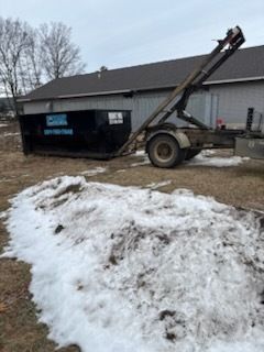 Snow pile in front of a house with a trailer-mounted lift or boom arm in the driveway.