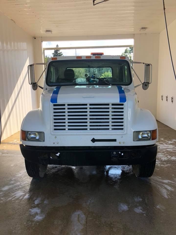 White International truck in a wash bay. Blue stripes on the hood.