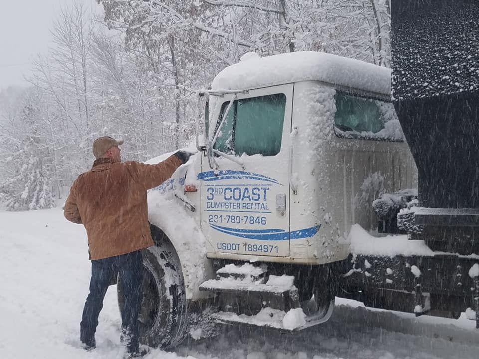 Man pointing at snow-covered truck with 